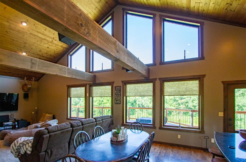 A living room with a table and chairs and a lot of windows.