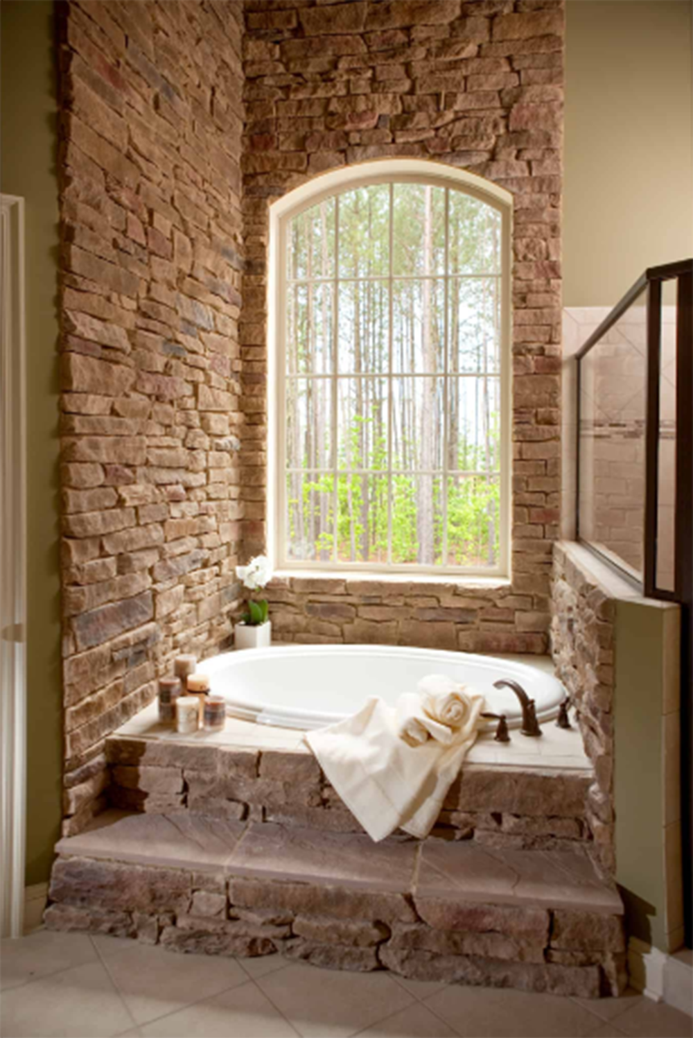 A bathtub in a bathroom with a brick wall and a window.
