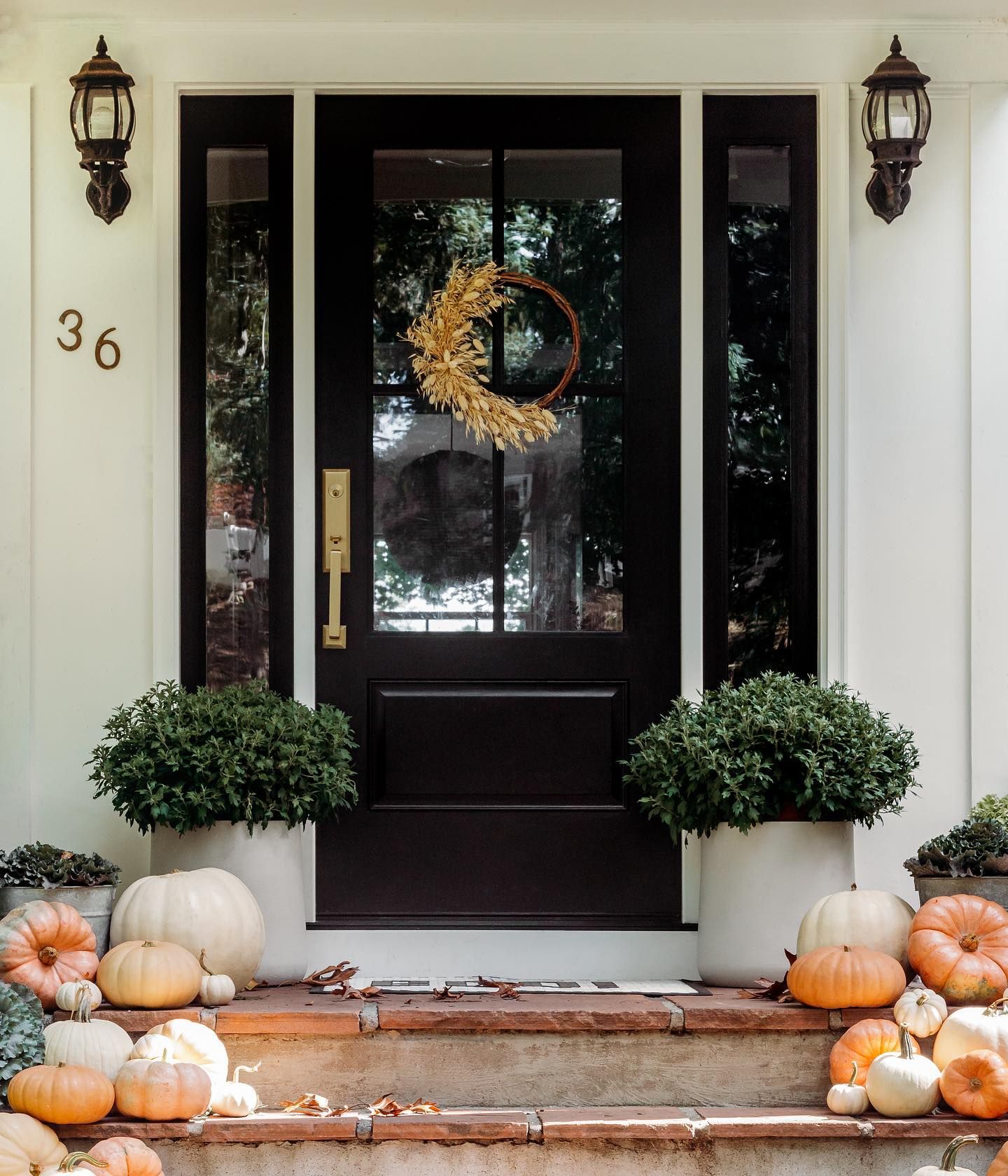 The front door of a house with pumpkins and a wreath on it