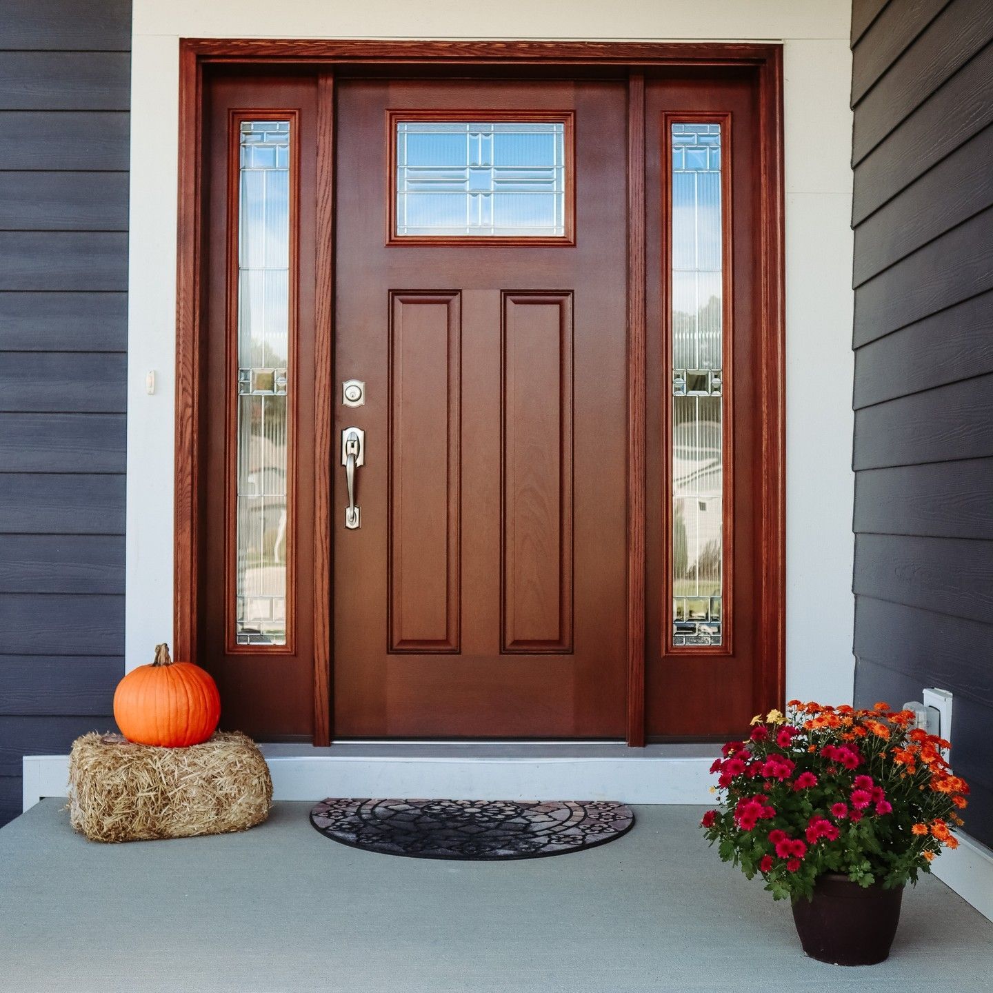 A wooden door with a pumpkin and flowers in front of it