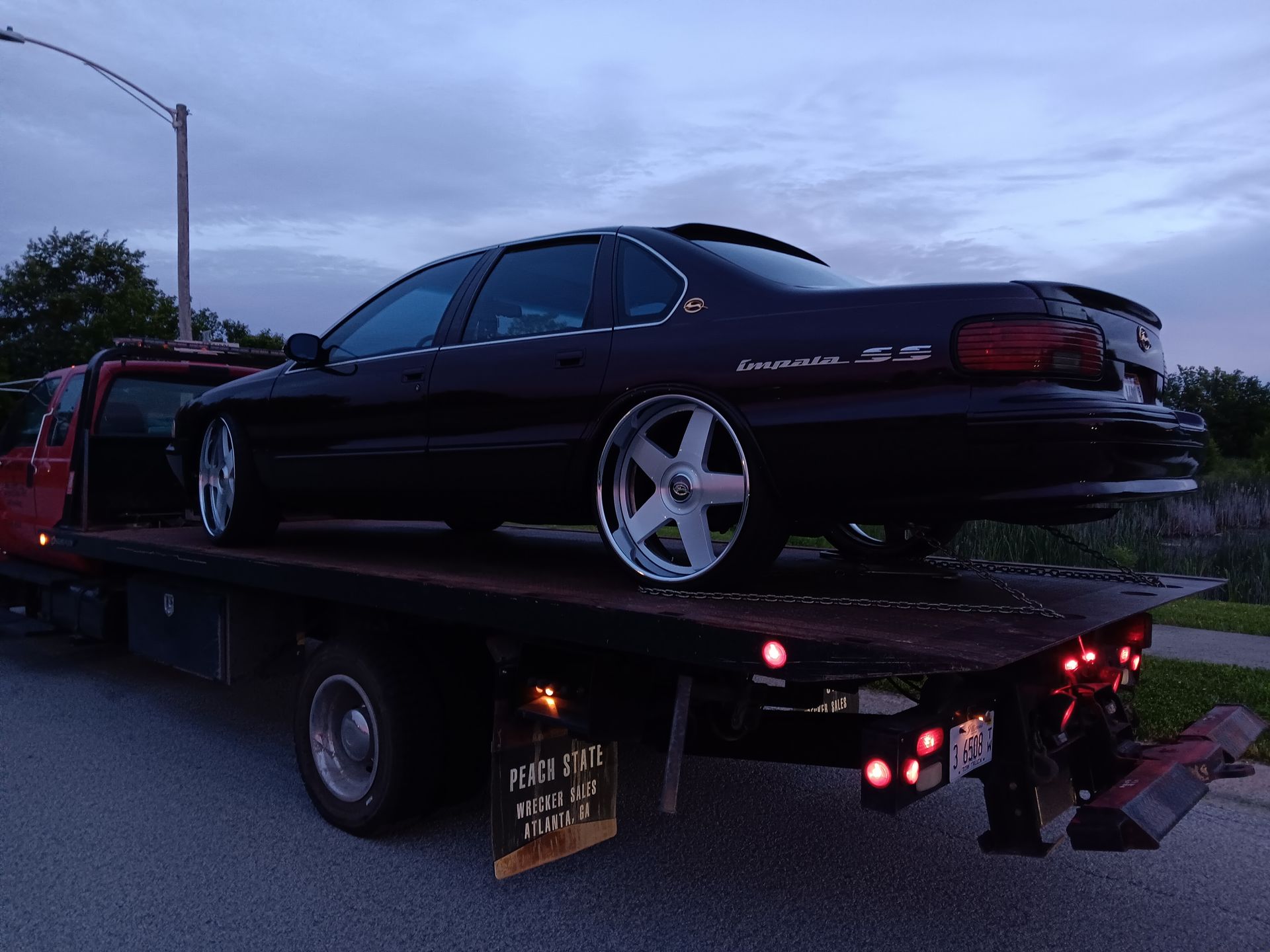 A black car is sitting on top of a tow truck