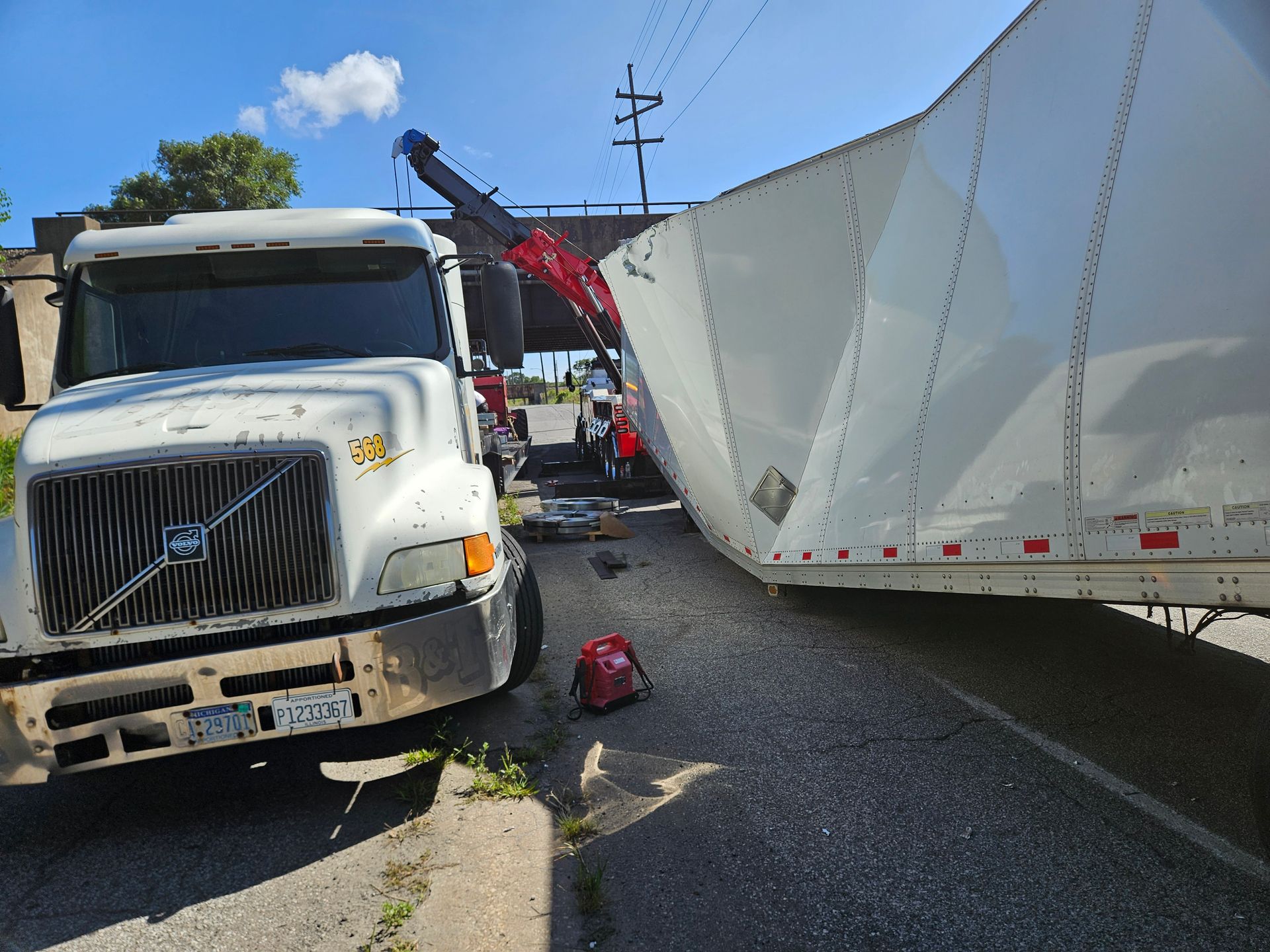 A volvo semi truck is being towed by a crane.