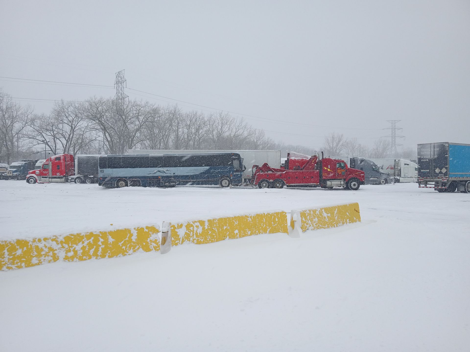 A group of trucks are parked in a snowy parking lot.