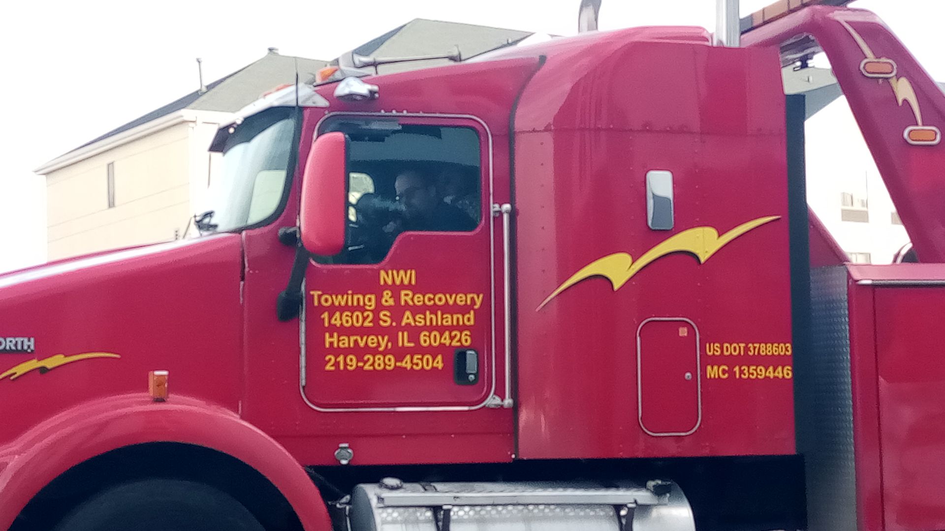 A red towing truck is parked in front of a house