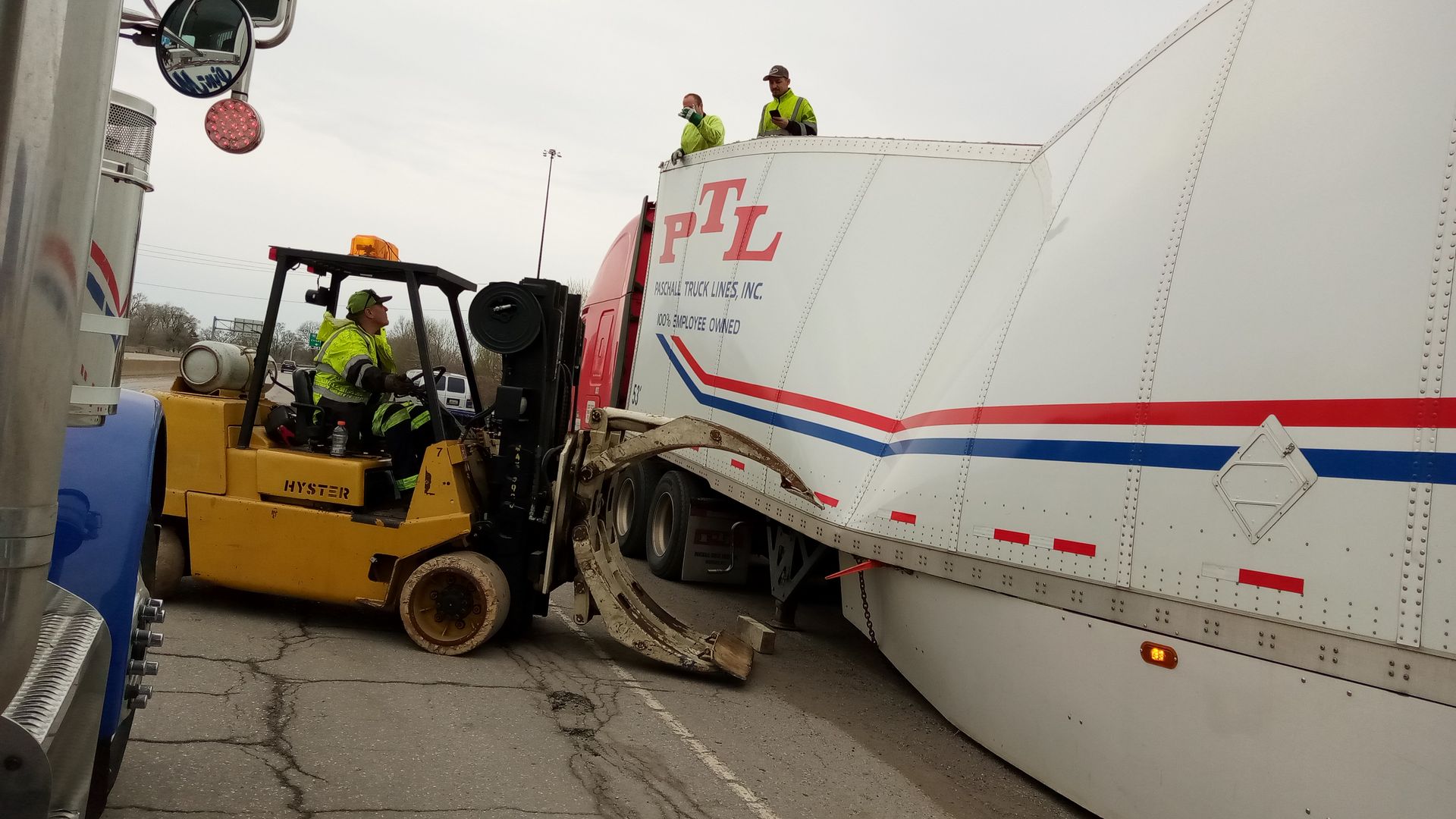 A forklift is stuck in the back of a semi truck.