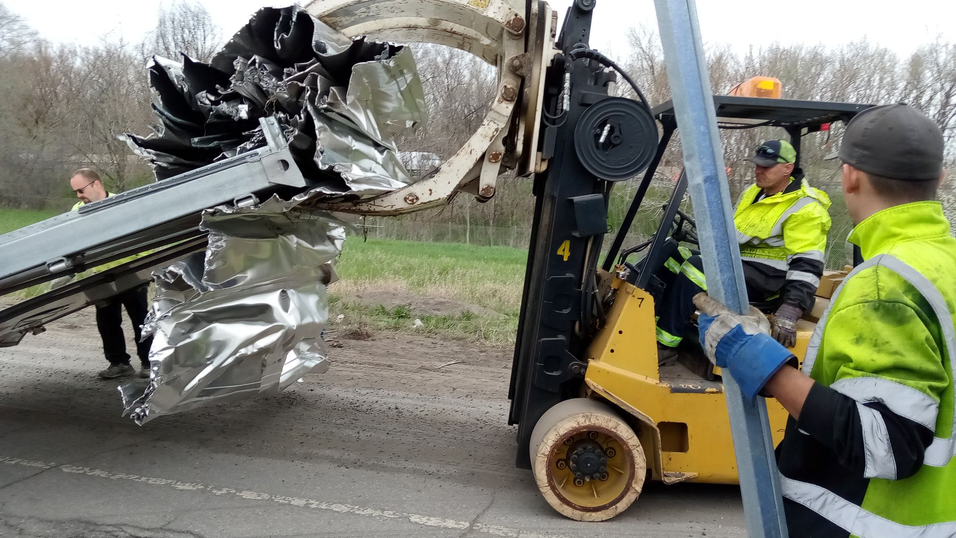 A forklift is carrying a large piece of metal on a road.