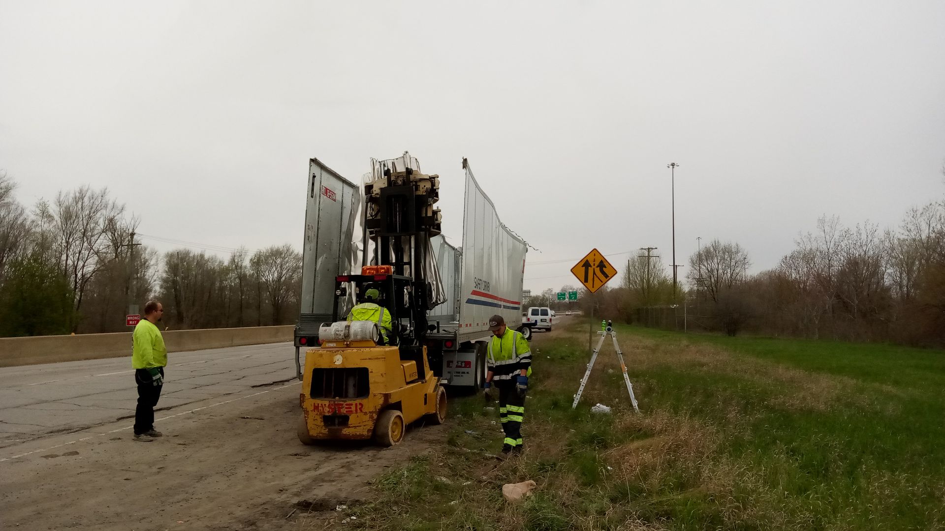 A forklift is loading a truck on the side of the road.