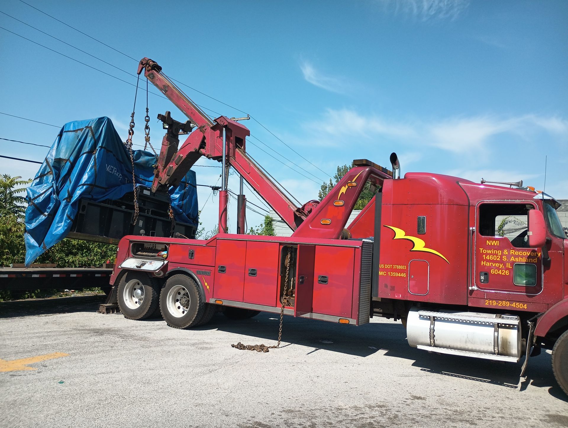 A red tow truck is carrying a blue tarp