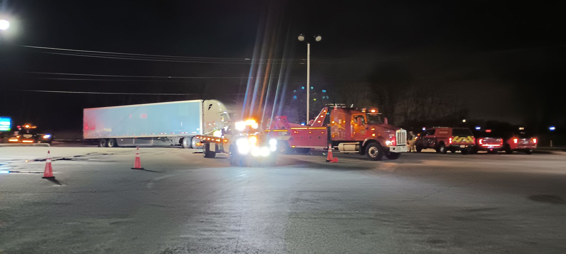A lot of trucks are parked in a parking lot at night.