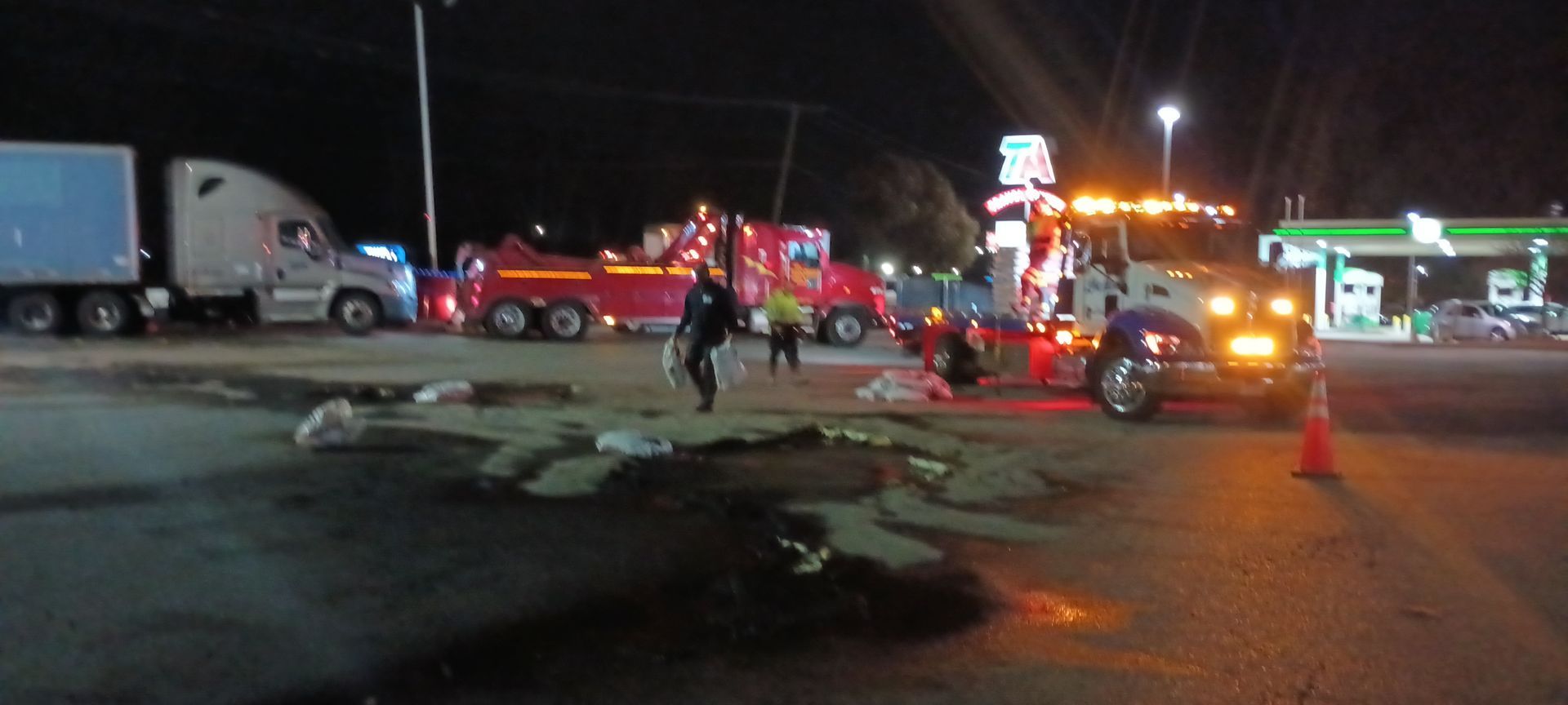 A tow truck is towing a truck in a parking lot at night.