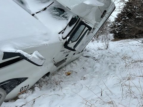 A white truck is upside down in the snow.