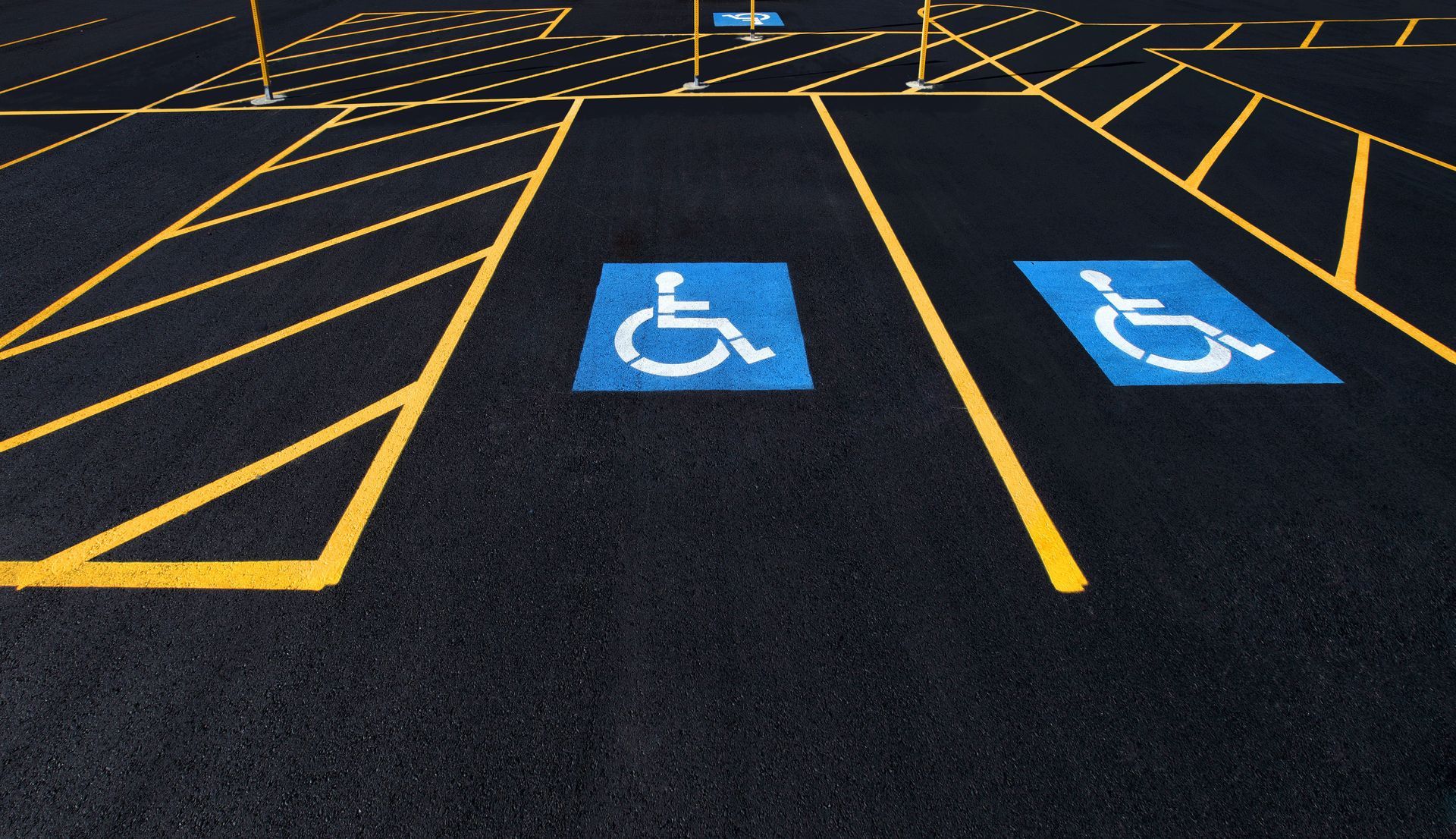 Empty accessible parking spaces marked with blue wheelchair symbols on a black parking lot