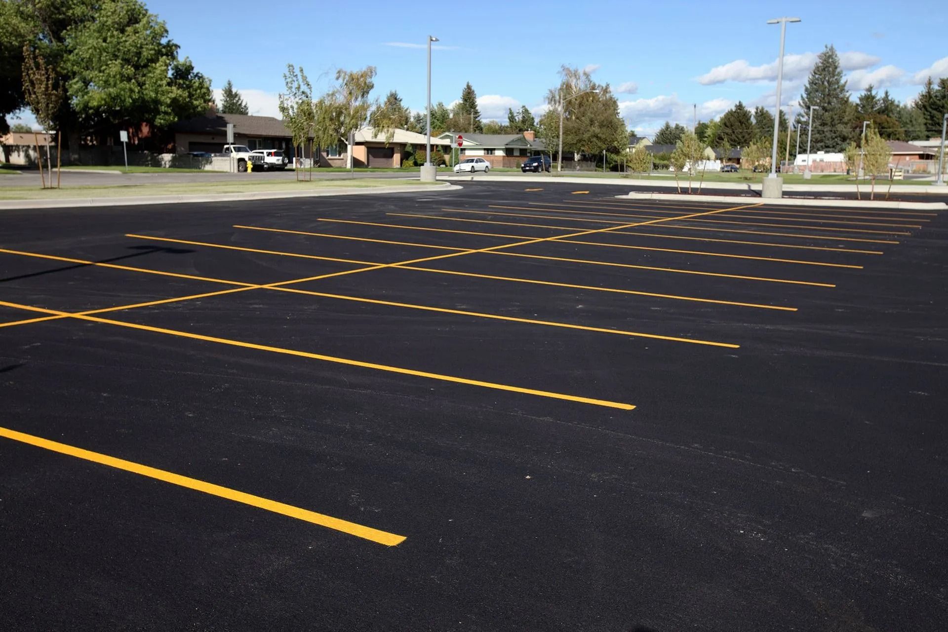 Empty asphalt parking lot with yellow painted lines under a blue sky