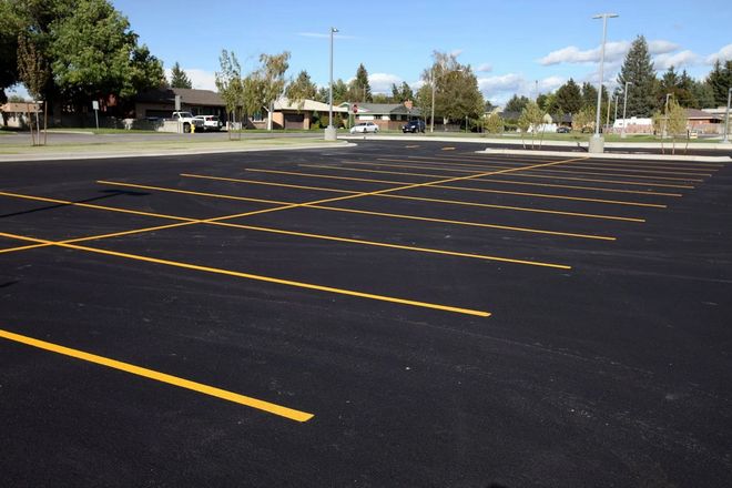 Empty asphalt parking lot with yellow painted lines under a blue sky