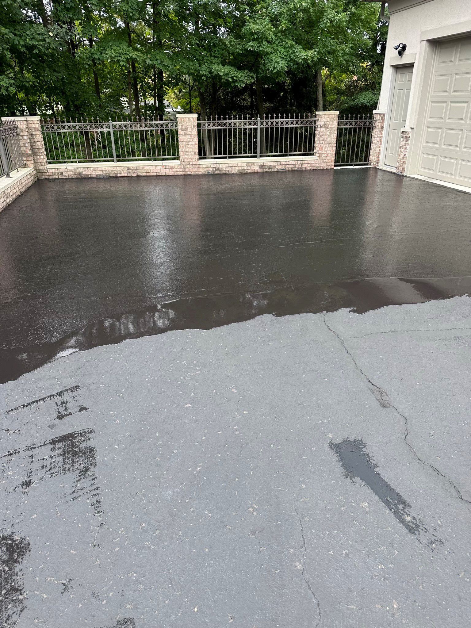 A concrete driveway with a fence and trees in the background.