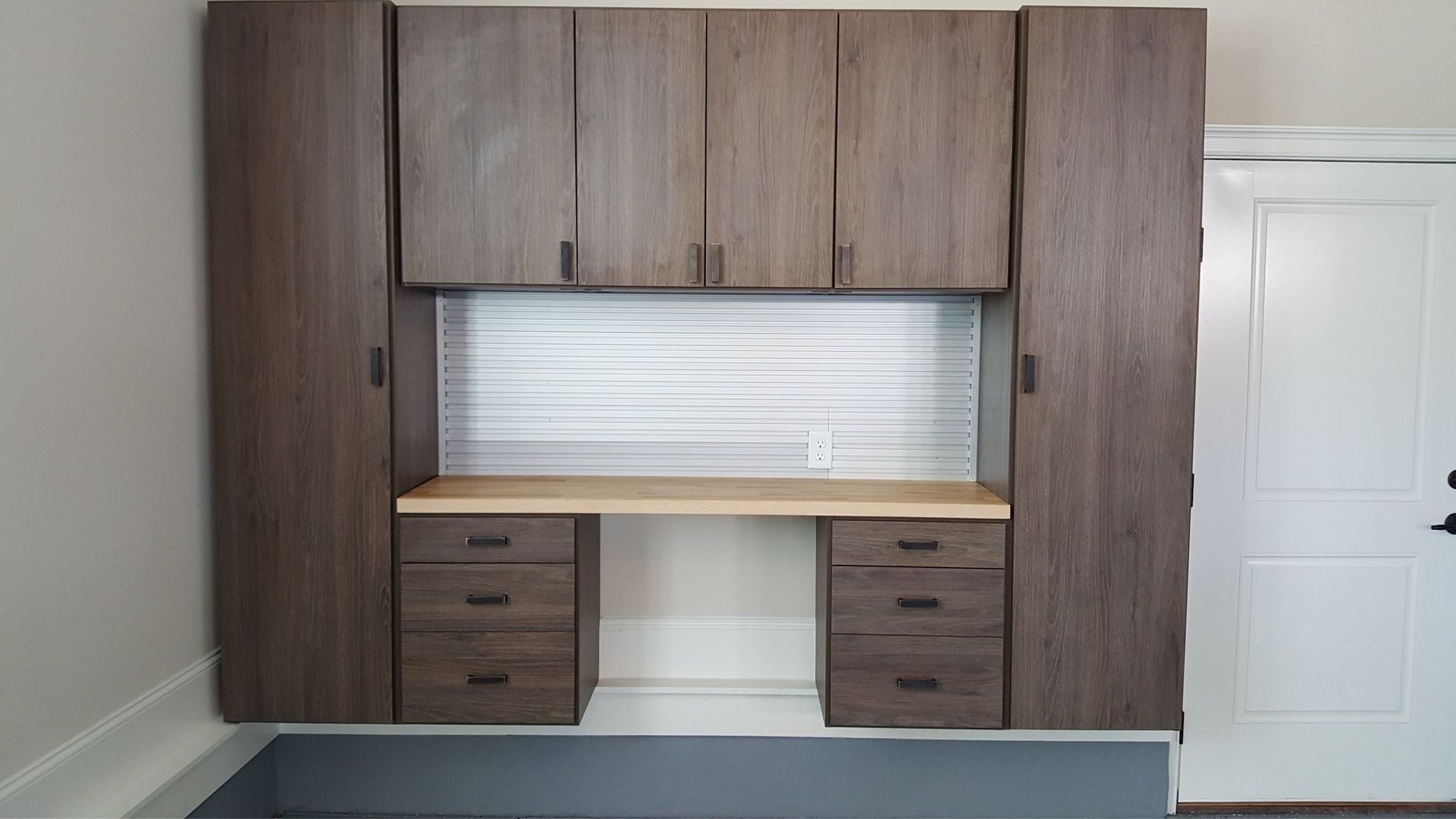 A garage with lots of cabinets and drawers and a desk.