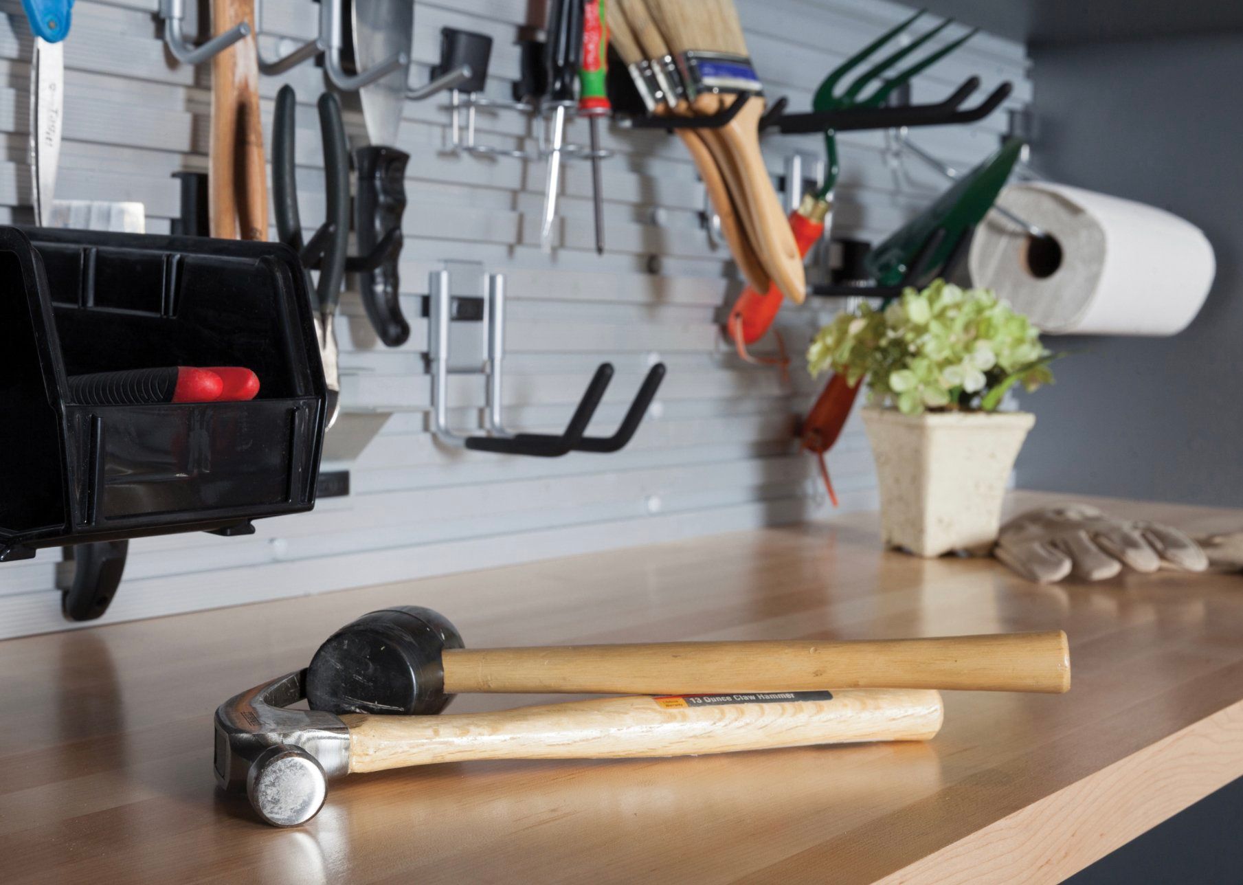 Two hammers are sitting on a wooden table in a garage.