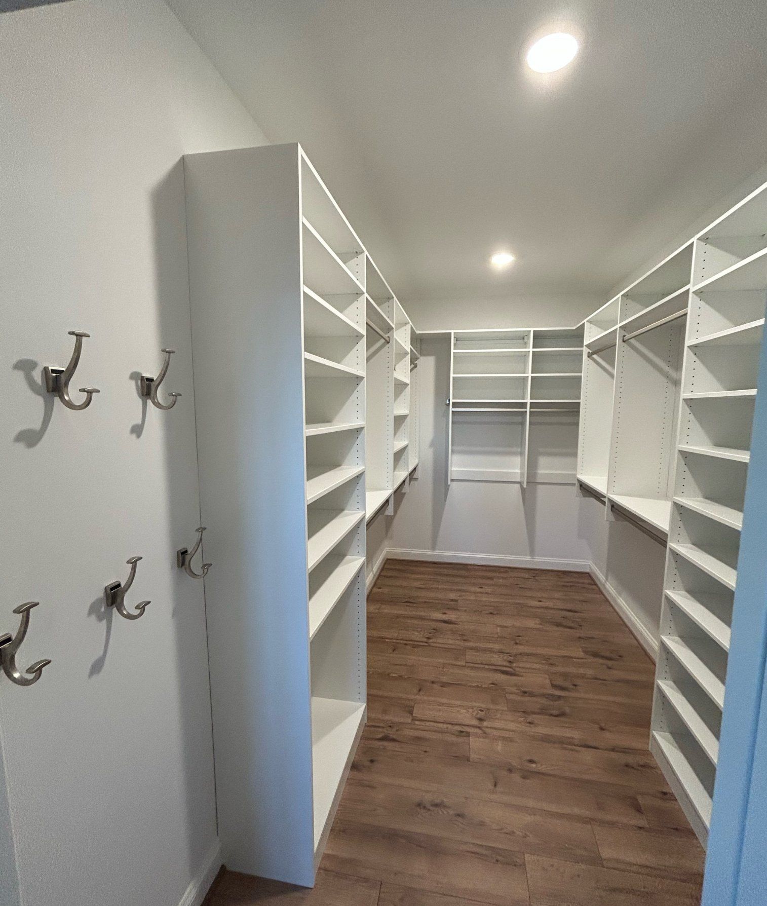 A walk in closet with lots of shelves and hooks