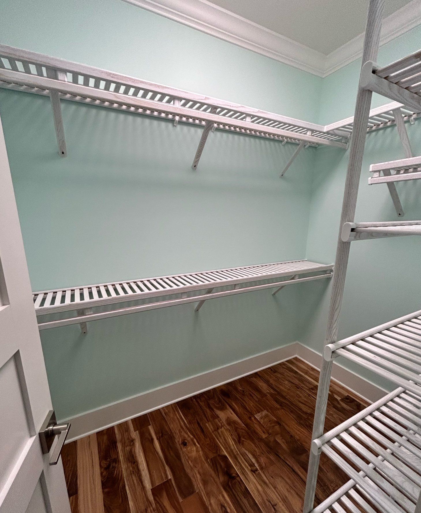 A walk in closet with wooden floors and shelves.