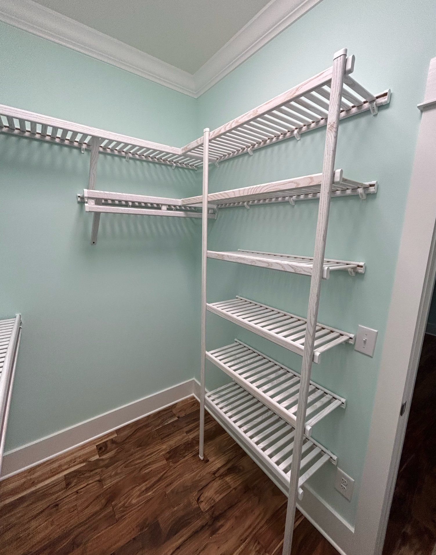 A walk in closet with lots of shelves and a wooden floor.