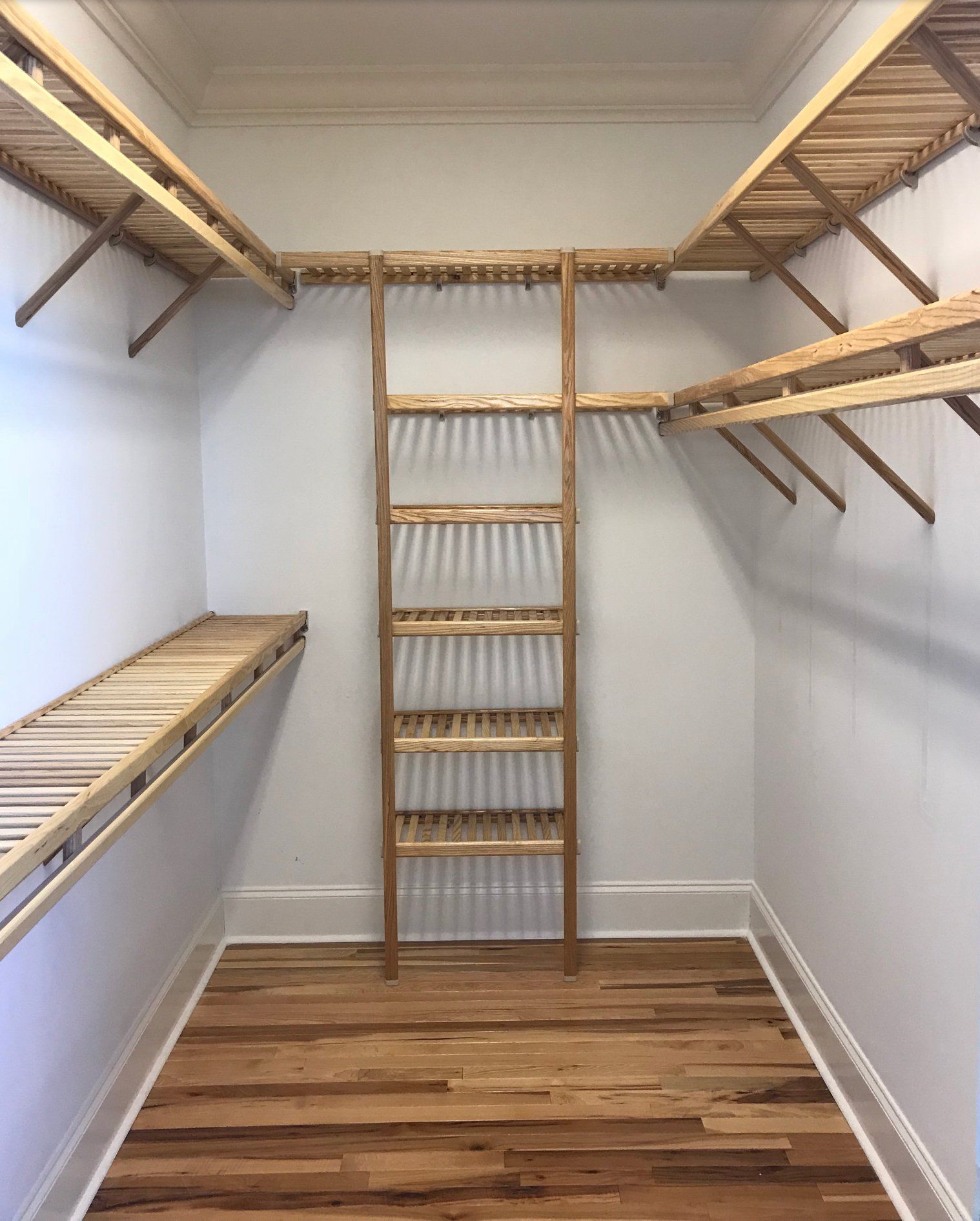 A walk in closet with wooden shelves and a ladder