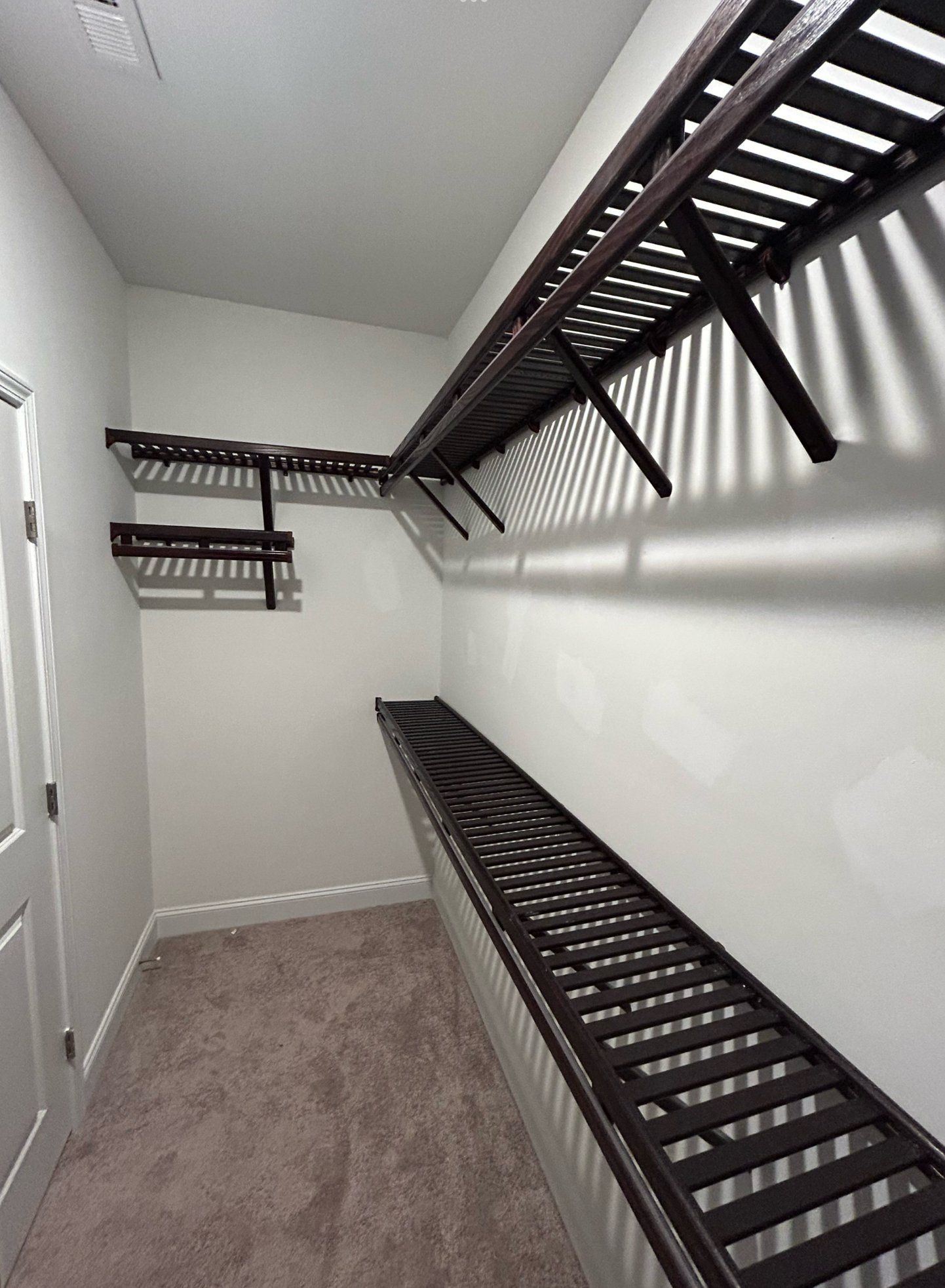 A walk in closet with a lot of shelves and a carpeted floor.
