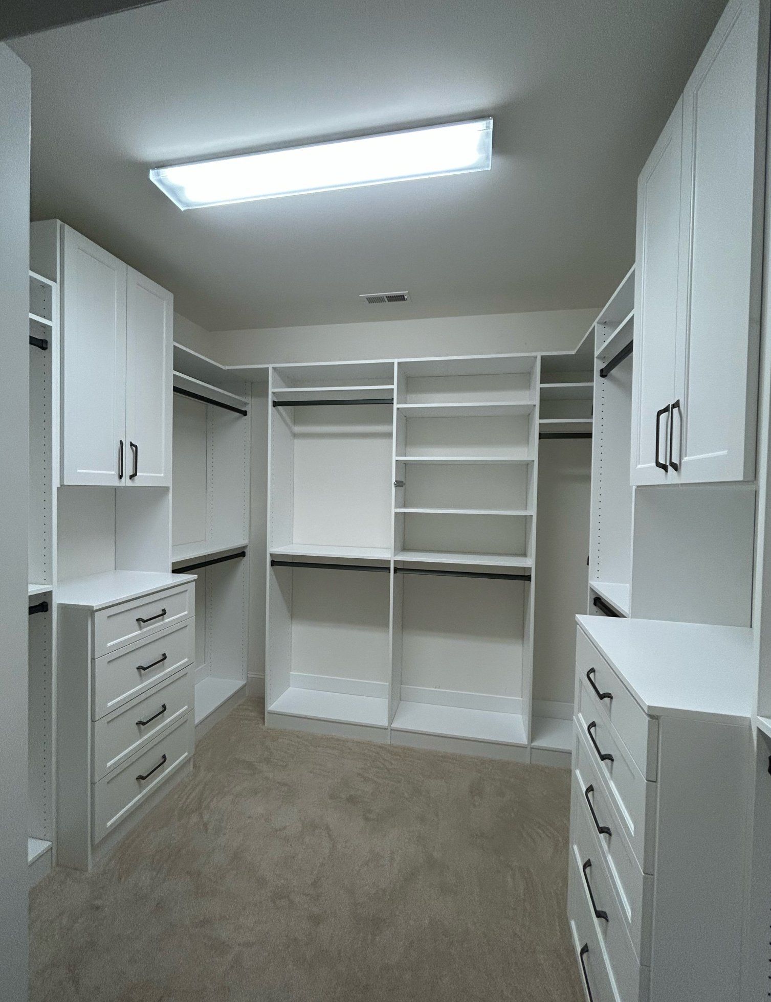 A walk in closet with white cabinets and drawers