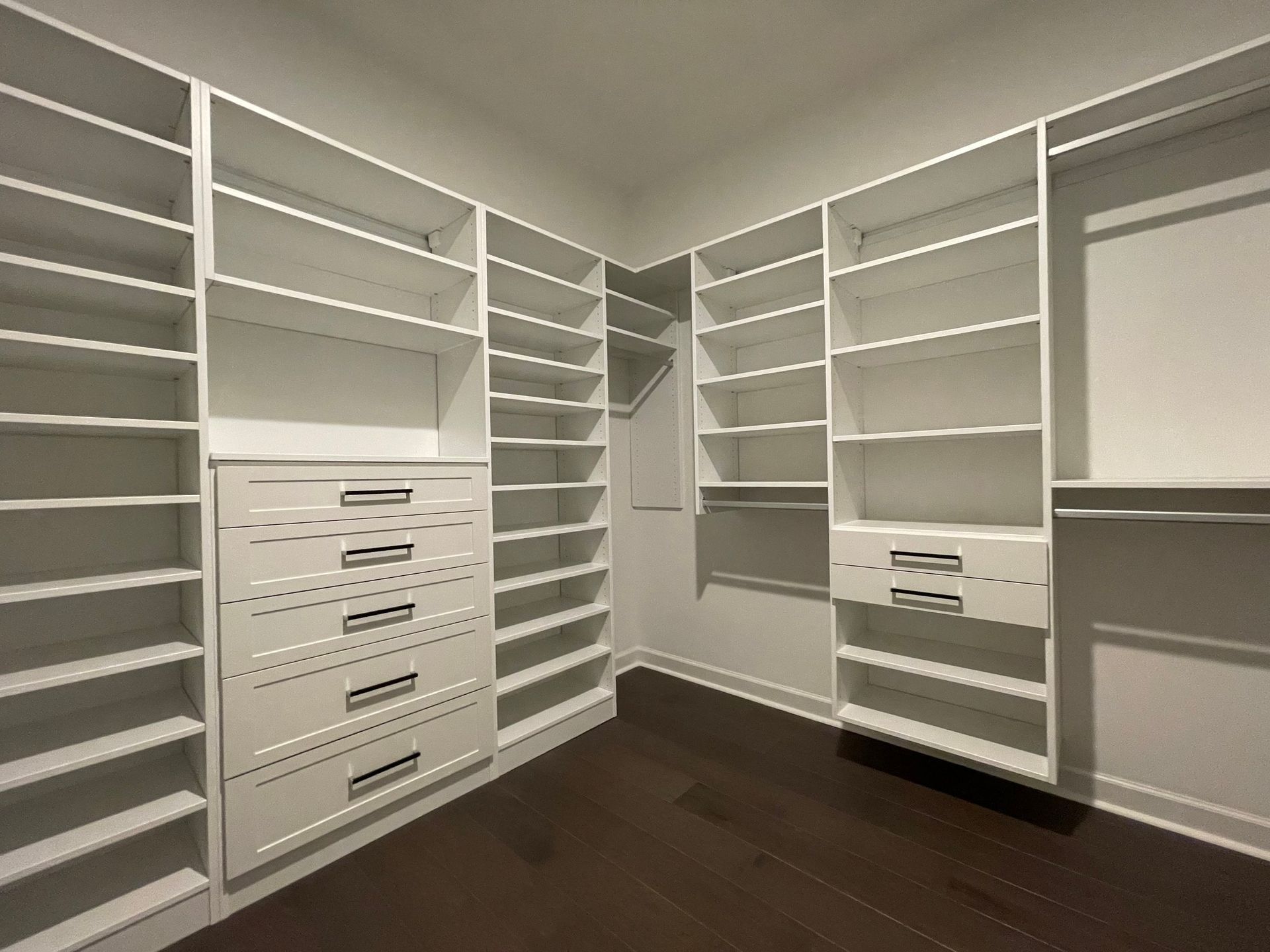 A walk in closet with lots of shelves and drawers
