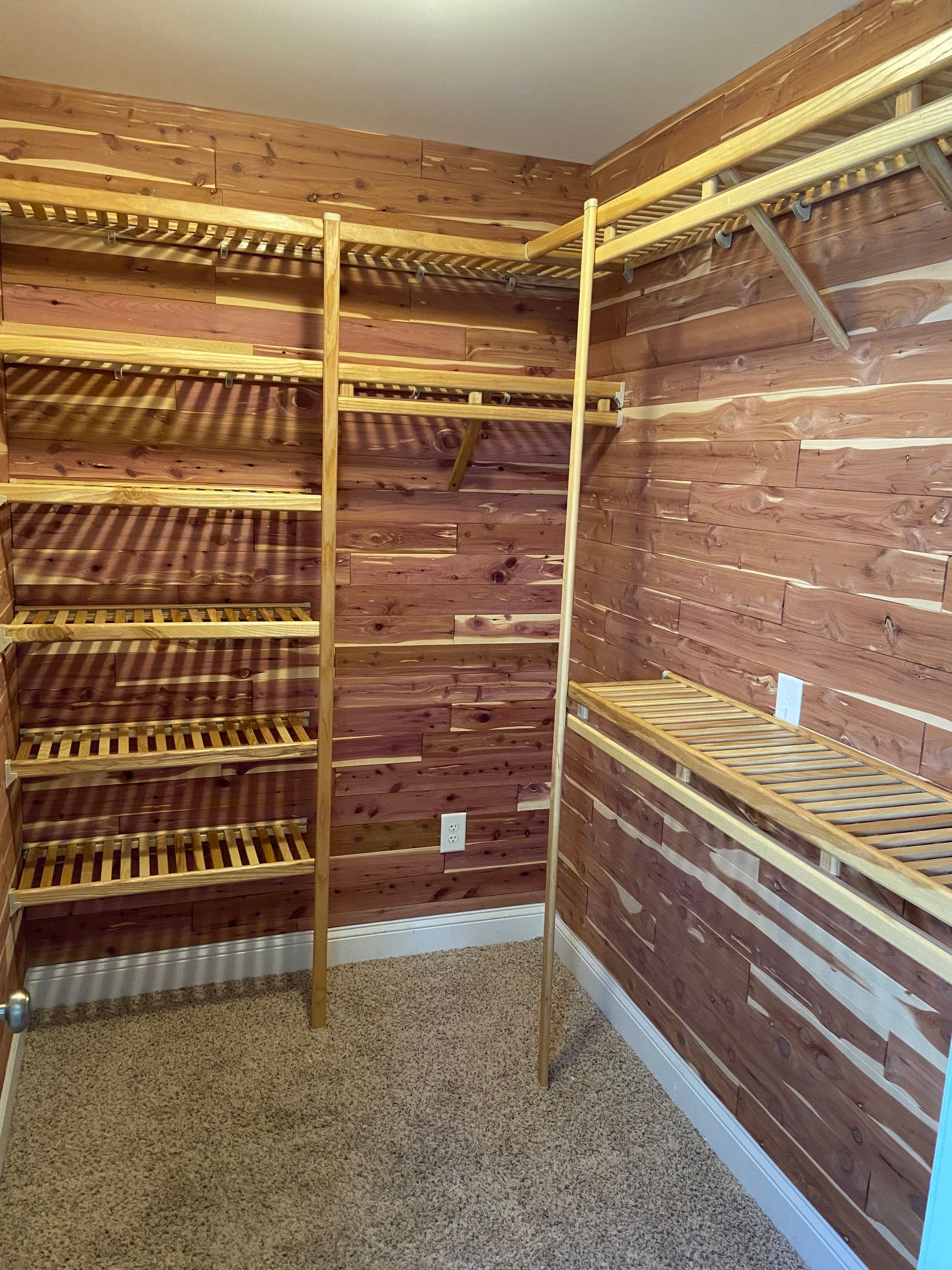 A walk in closet with wooden shelves and a wooden wall.