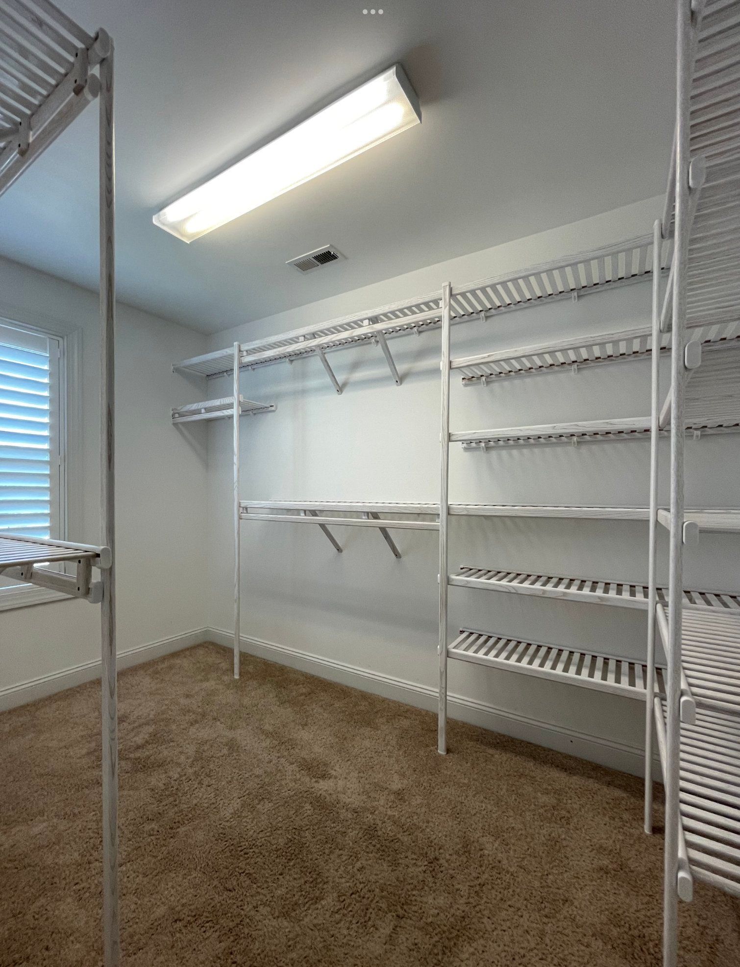 A walk in closet with a lot of shelves and a light on the ceiling.