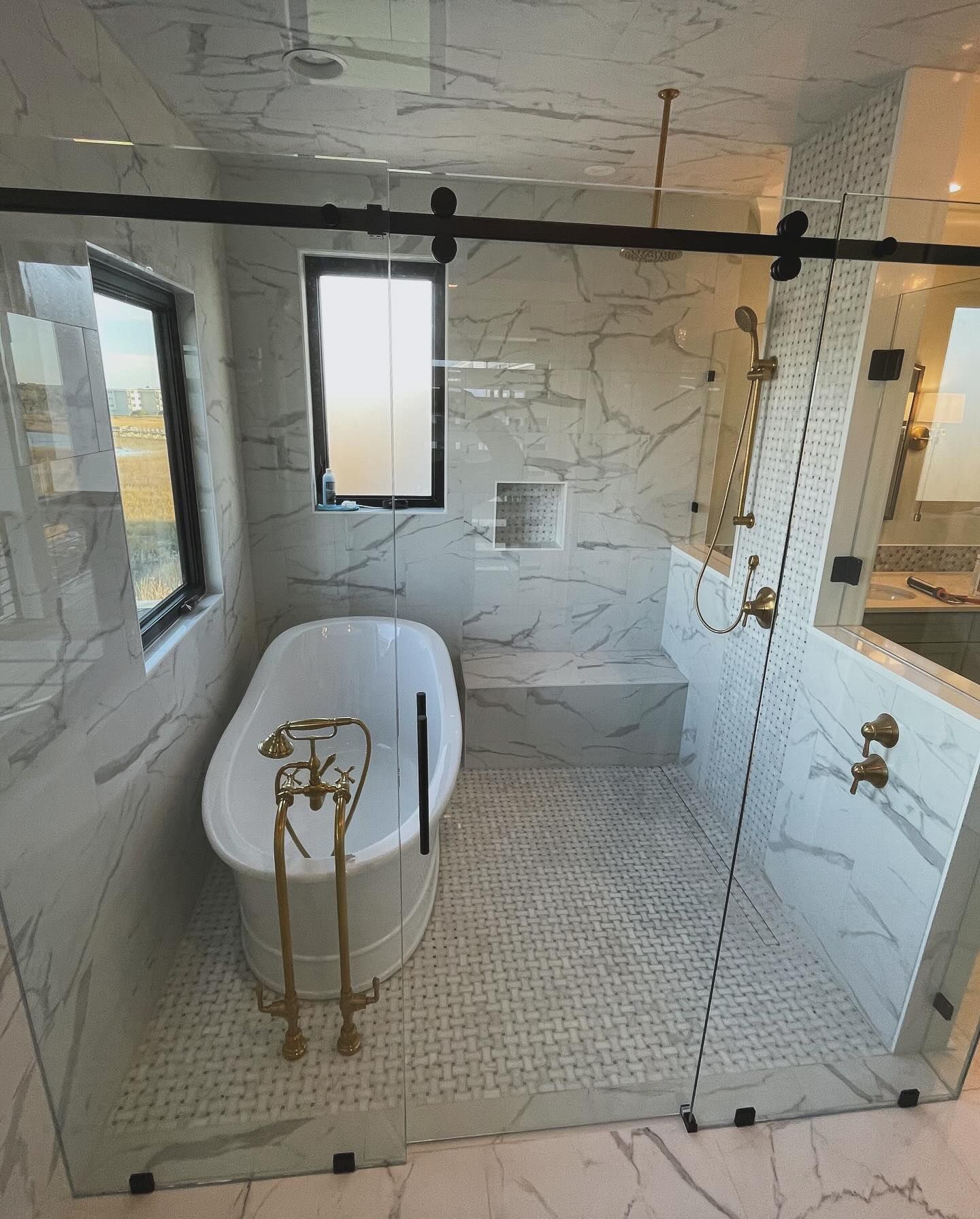 A bathroom with a tub and a shower with a sliding glass door.