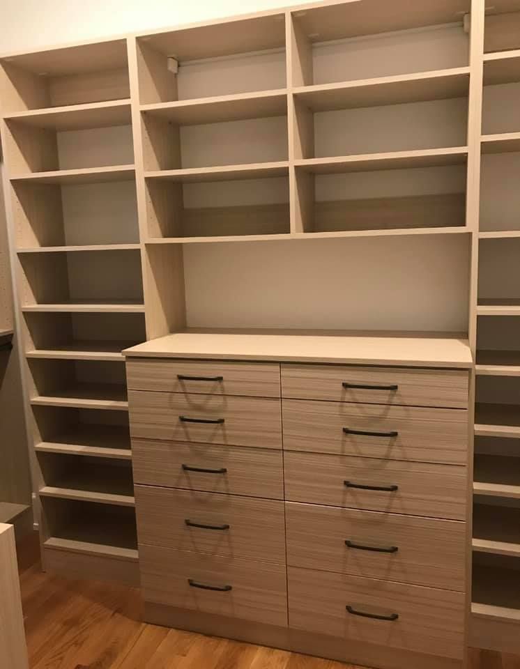 A walk in closet with lots of shelves and drawers.
