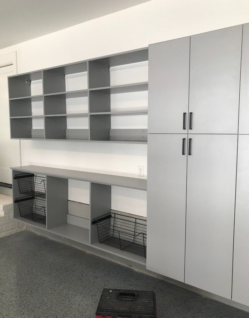 A garage with lots of shelves and cabinets and a toolbox on the floor.