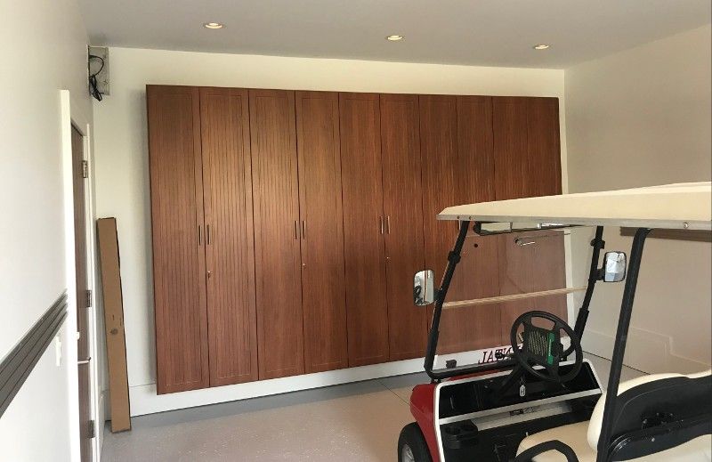 A golf cart is parked in a garage with wooden cabinets.