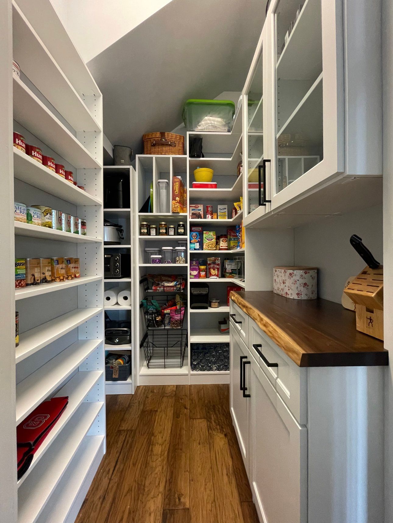 A pantry with lots of shelves and cabinets and a wooden counter top.