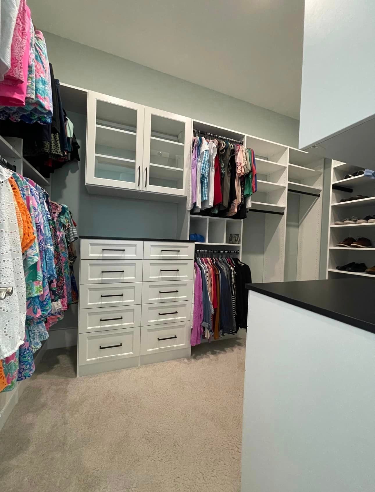 A walk in closet filled with lots of clothes and drawers.