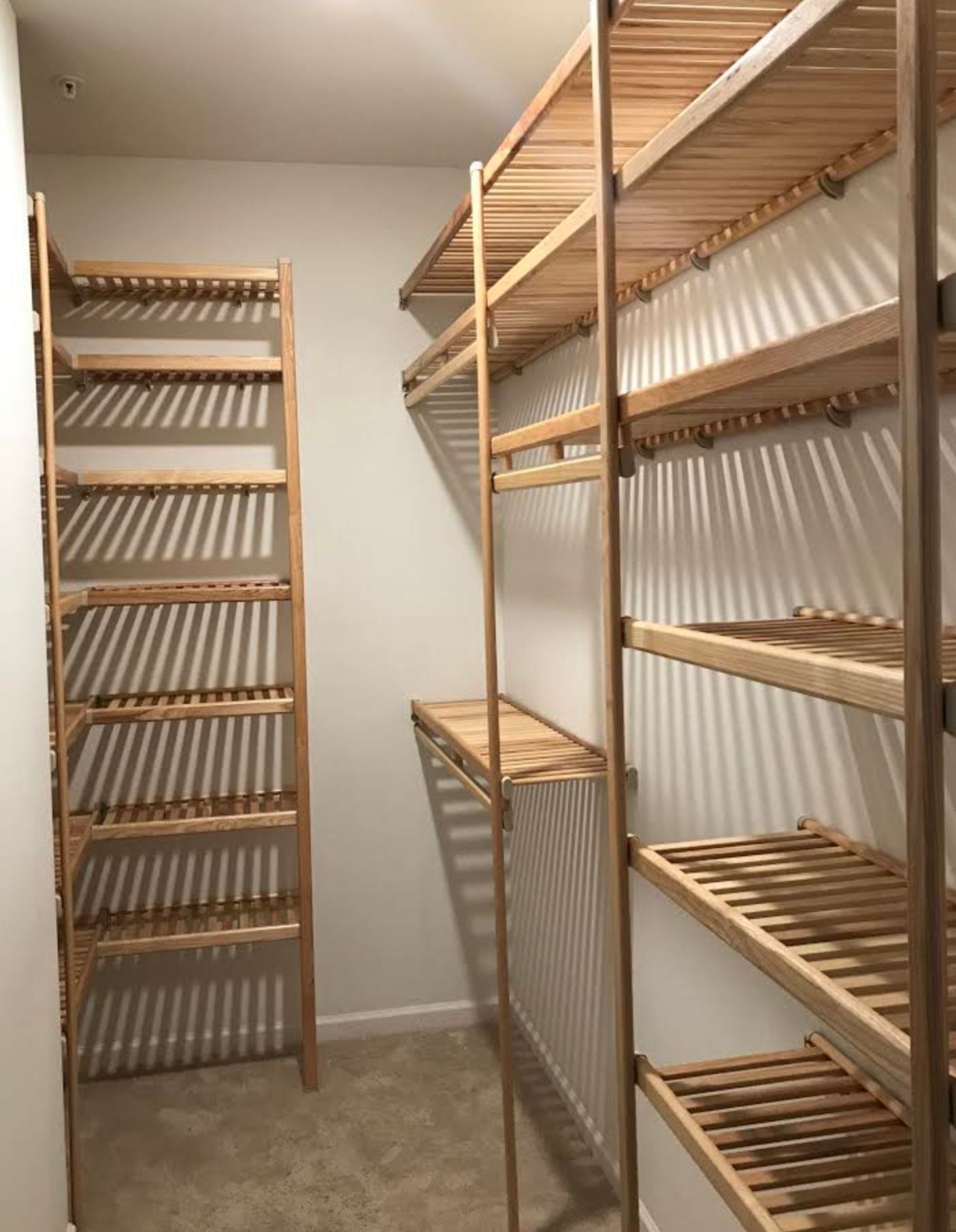 A walk in closet with wooden shelves and a ladder.