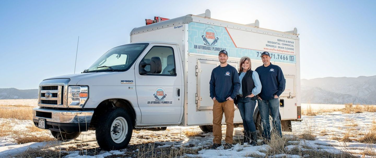 A group of people are standing in front of a white truck in a snowy field.