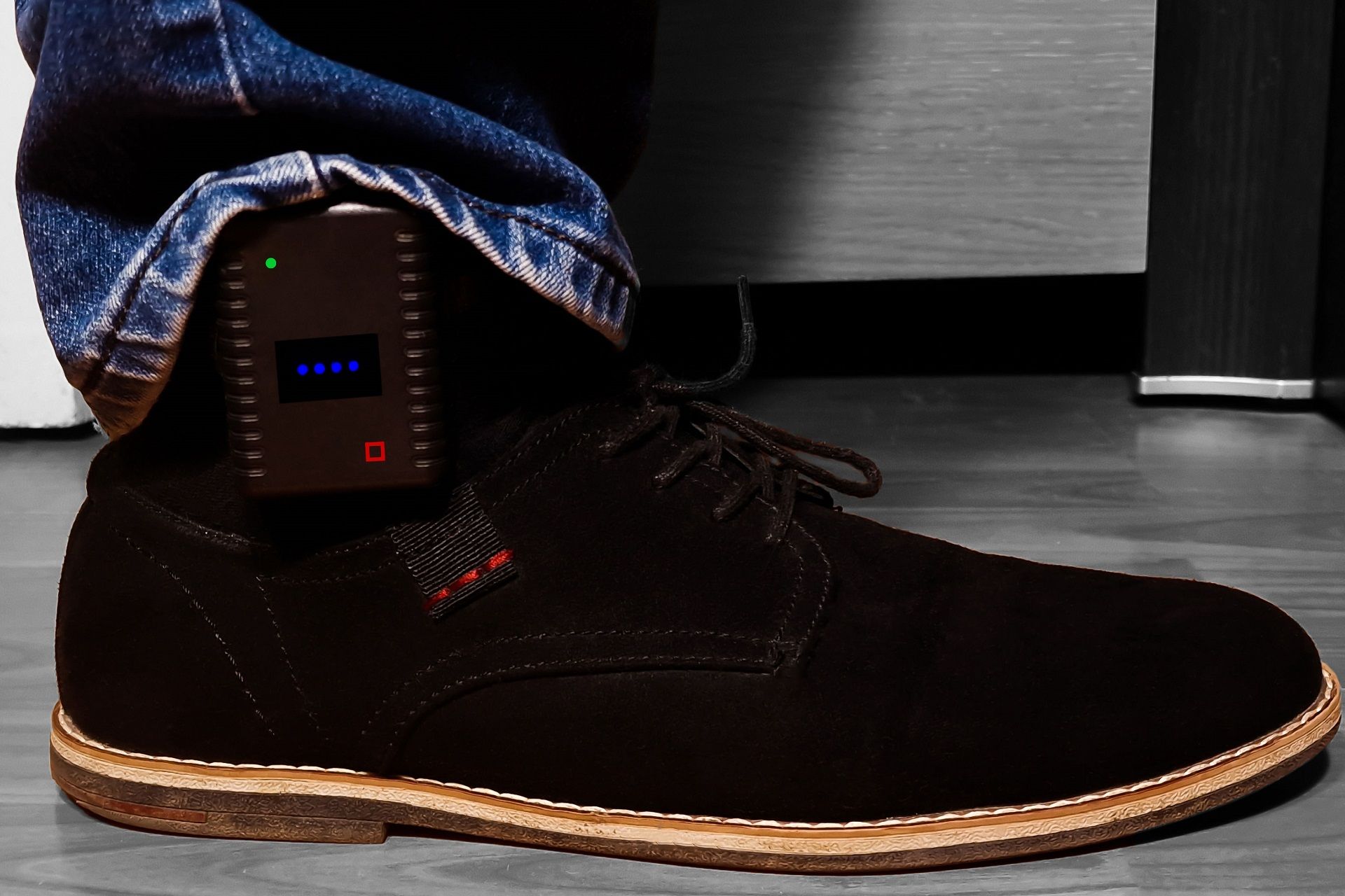 a person wearing a pair of black shoes with a small device attached to their ankle