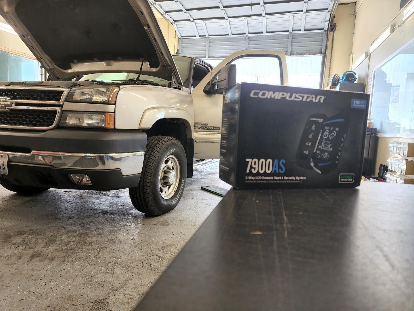 a truck with the hood up is parked in a garage next to a box .