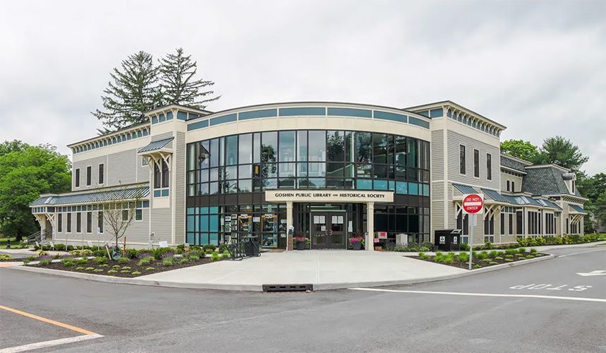 Modern two-story building with glass entrance and parking lot at the front
