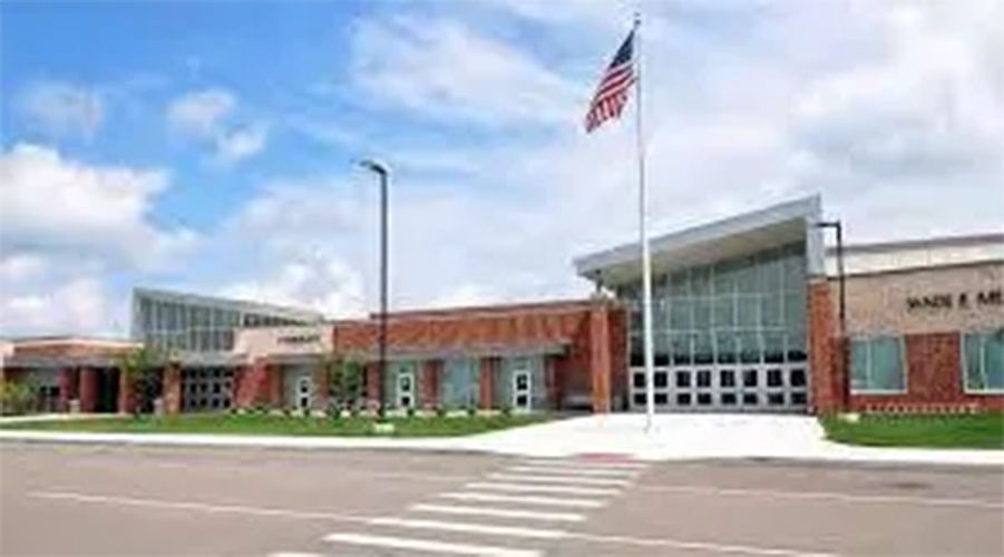 Modern school building with brick facade, glass entrance, and an American flag out front