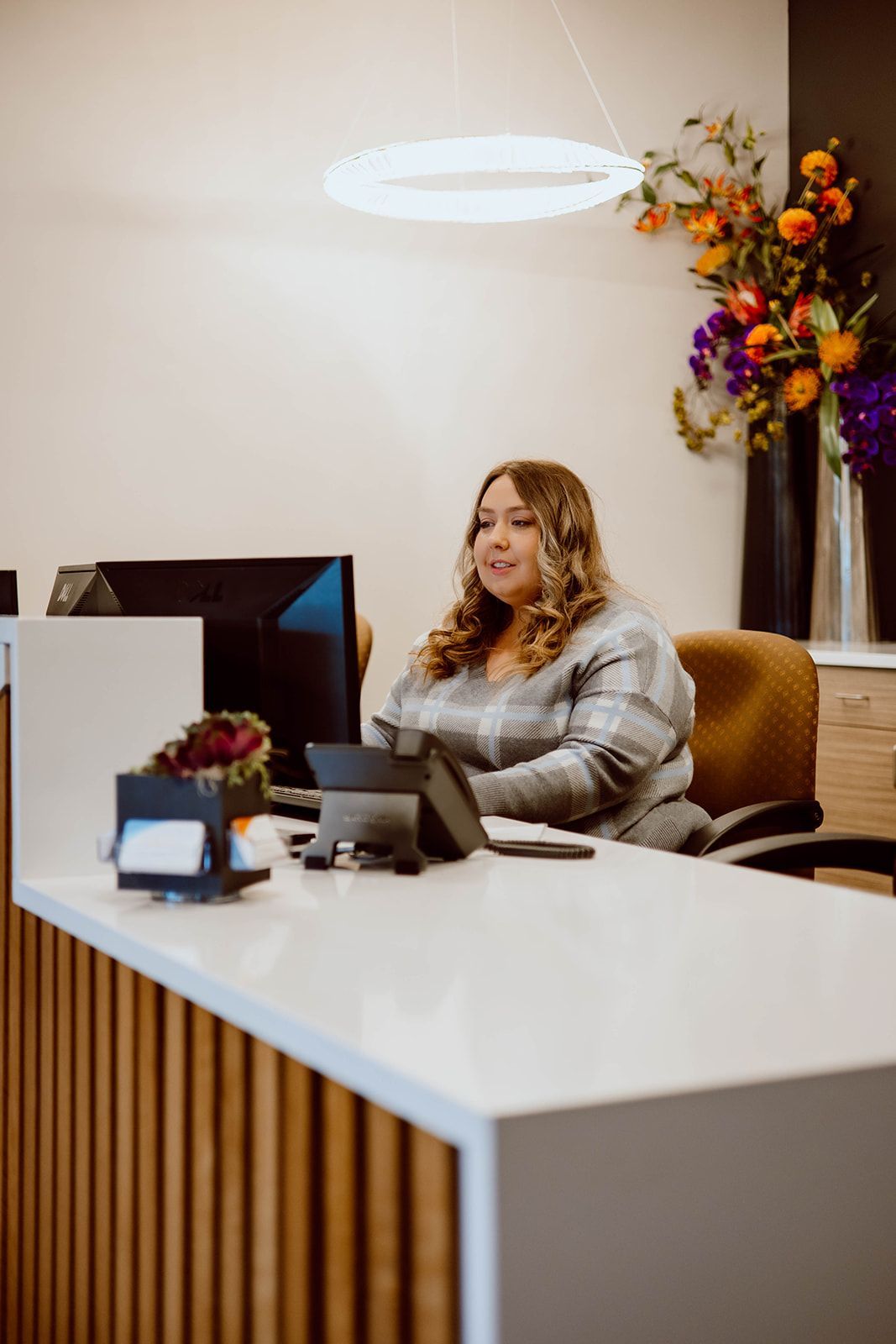 A woman is sitting at a desk in front of a computer.
