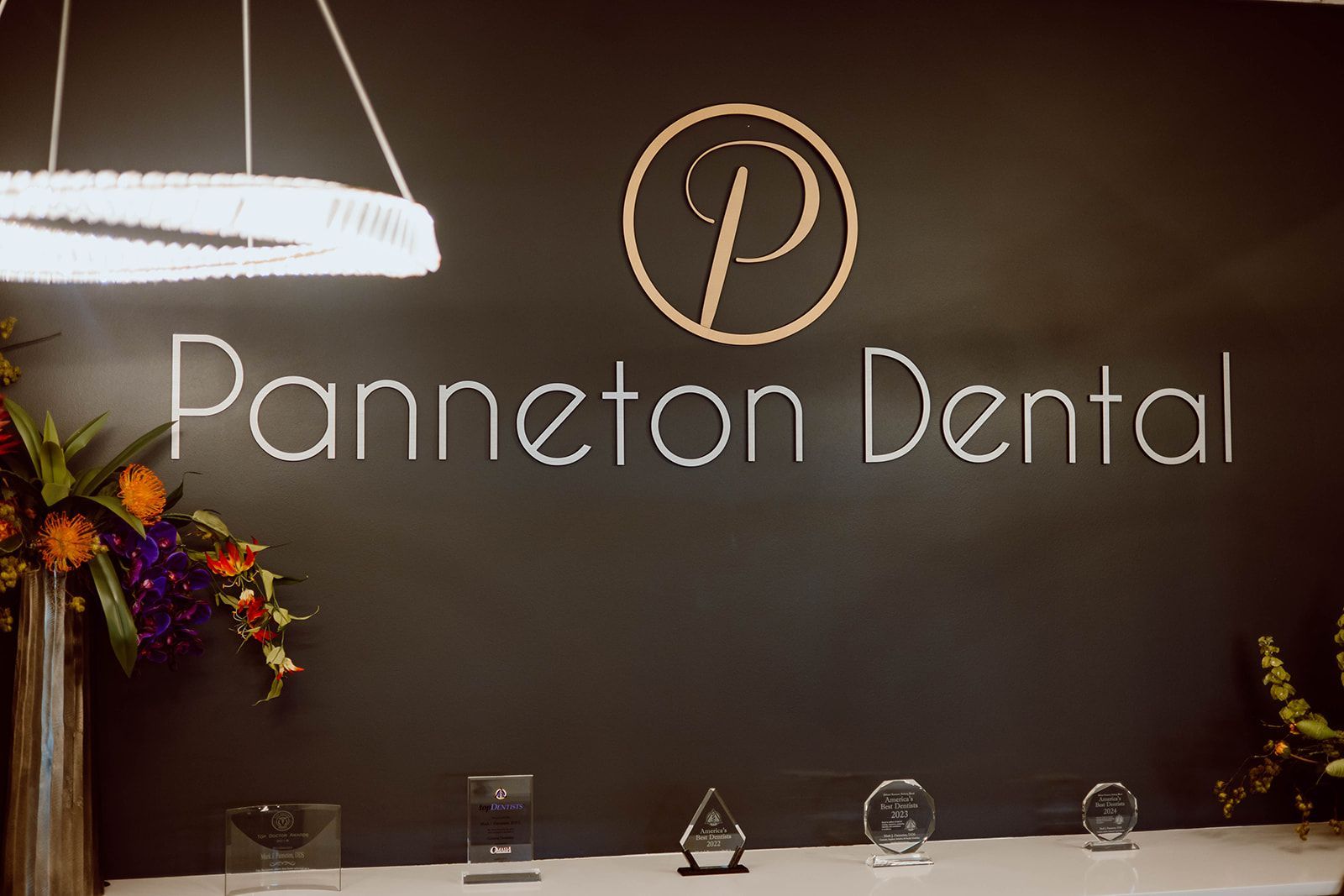 A sign for panneton dental is on a black wall.