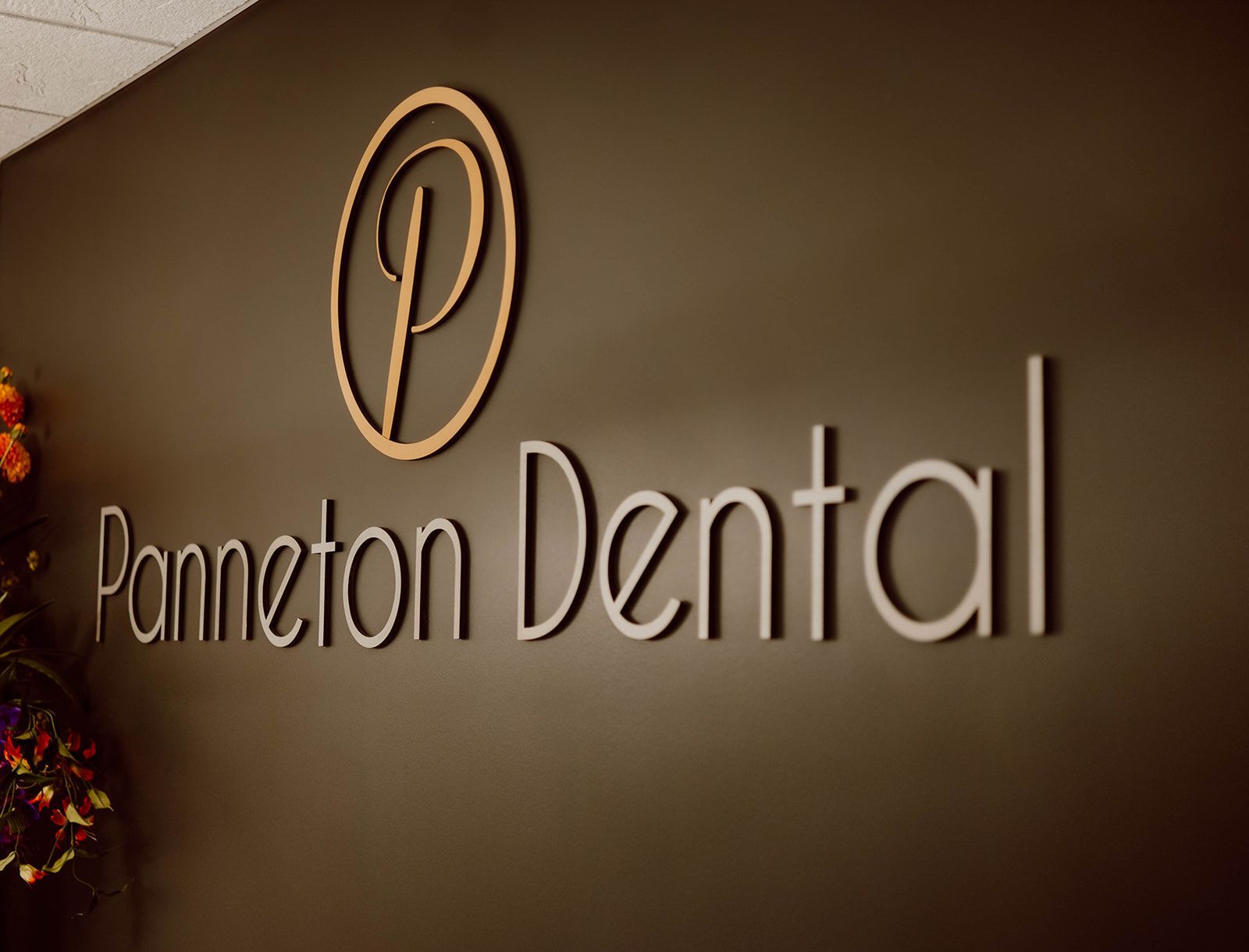 A sign for panneton dental is on a brown wall