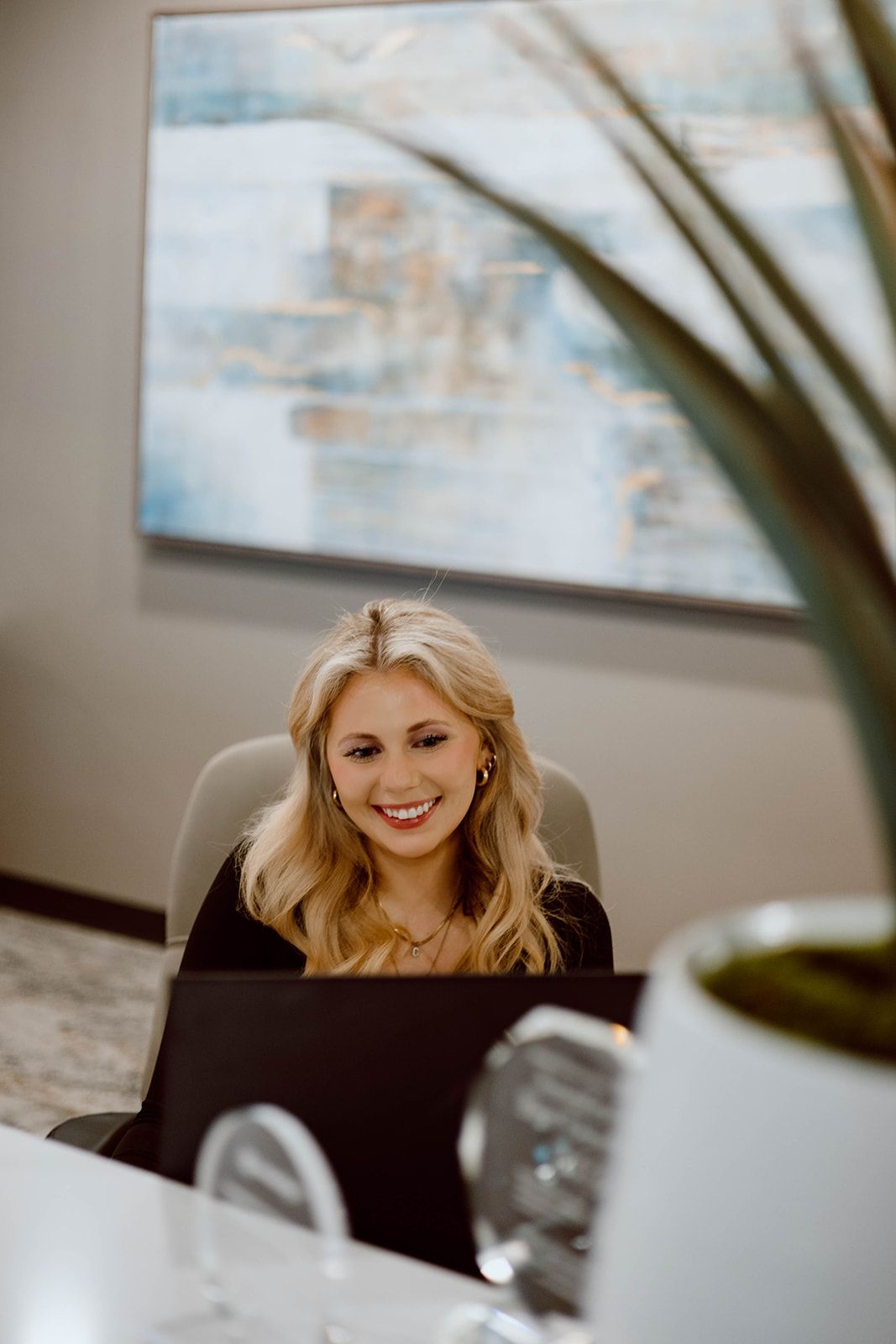 A woman is sitting at a desk in front of a laptop computer.