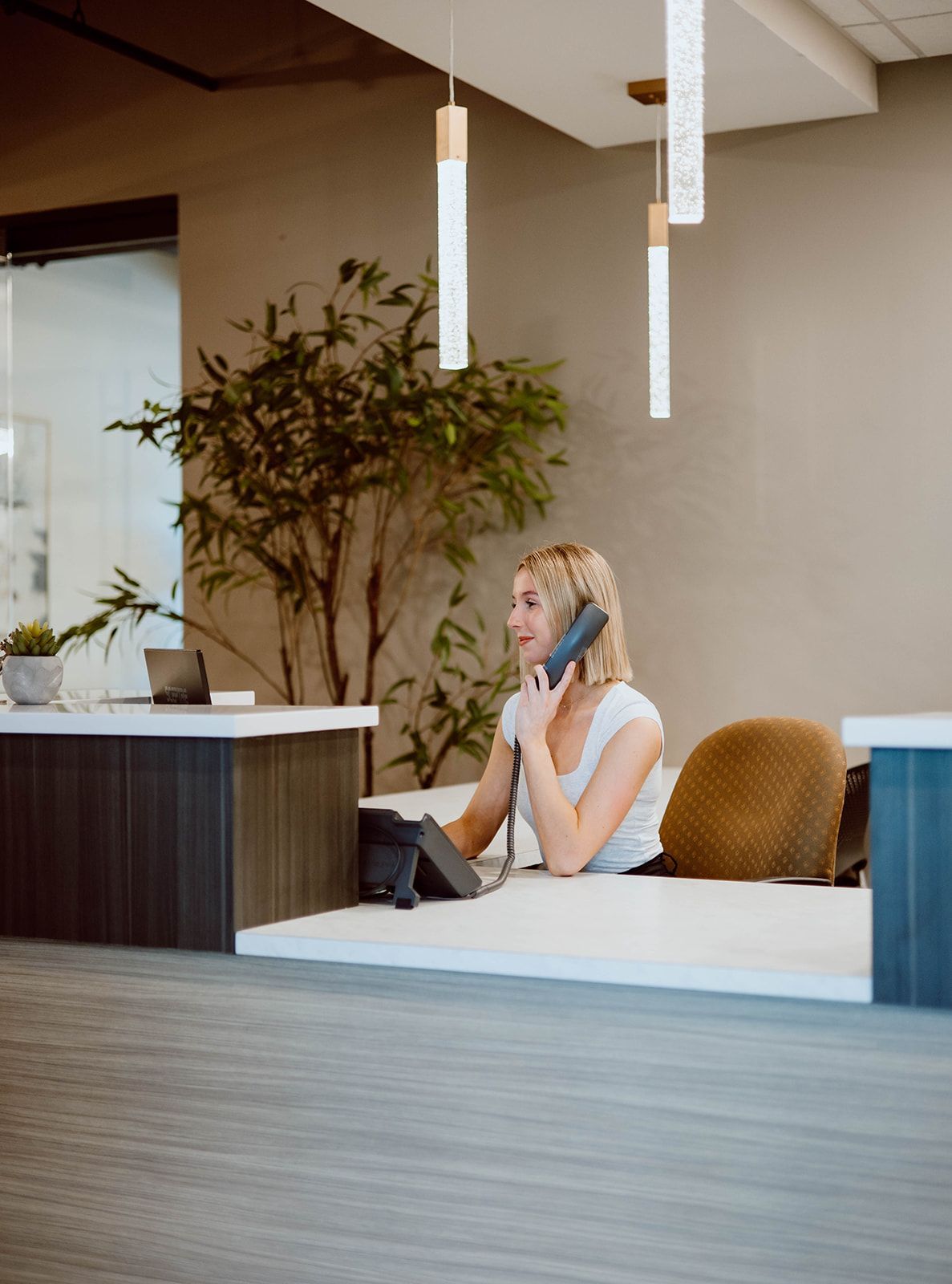 A woman is sitting at a desk talking on a phone.