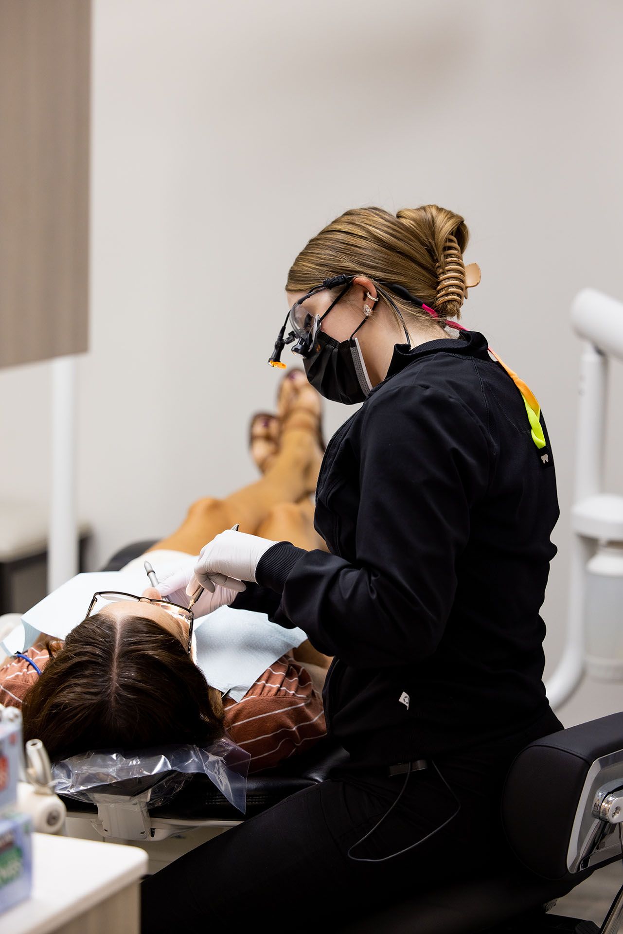 A dentist is examining a patient 's teeth in a dental office.