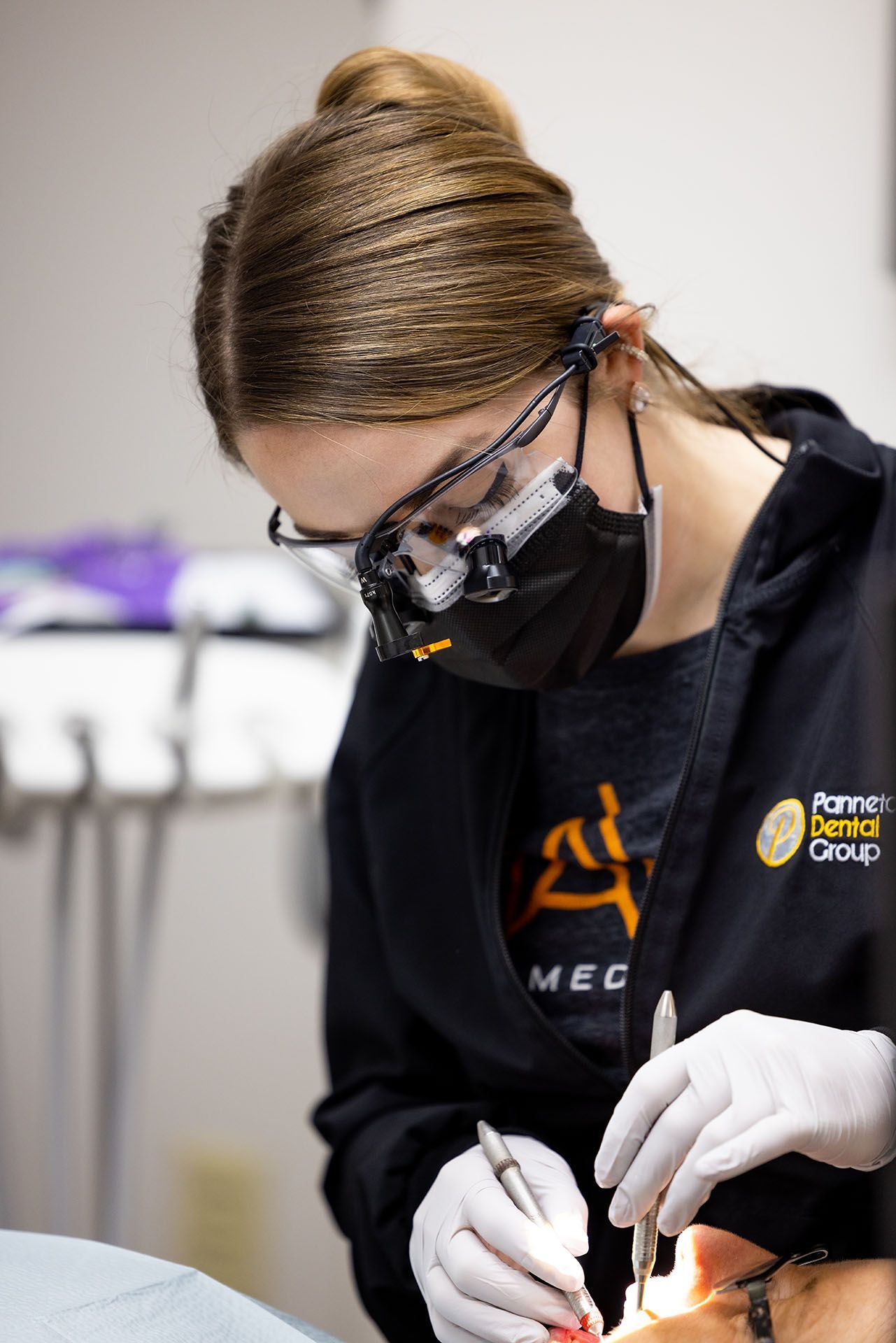A female dentist is examining a patient 's teeth in a dental office.