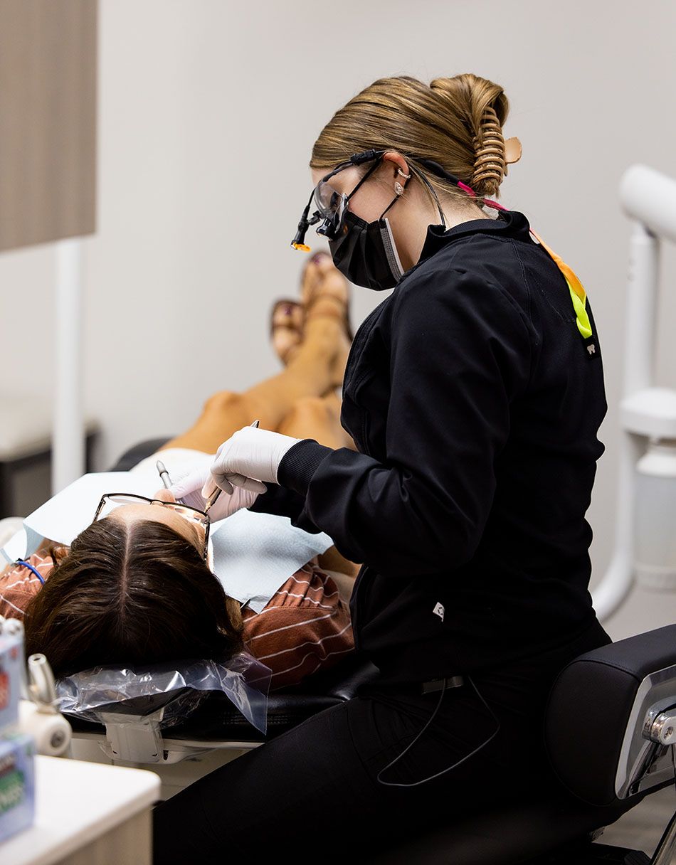 A dentist is examining a patient 's teeth in a dental office.